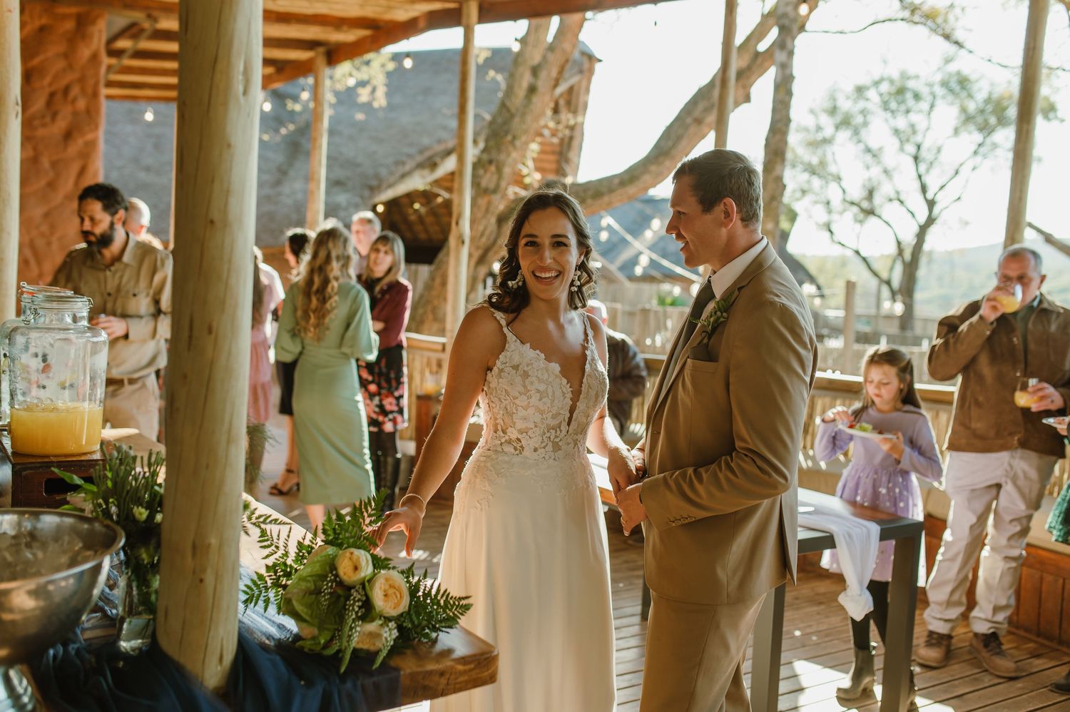 Wedding celebration under covered patio with rustic wooden pillars.