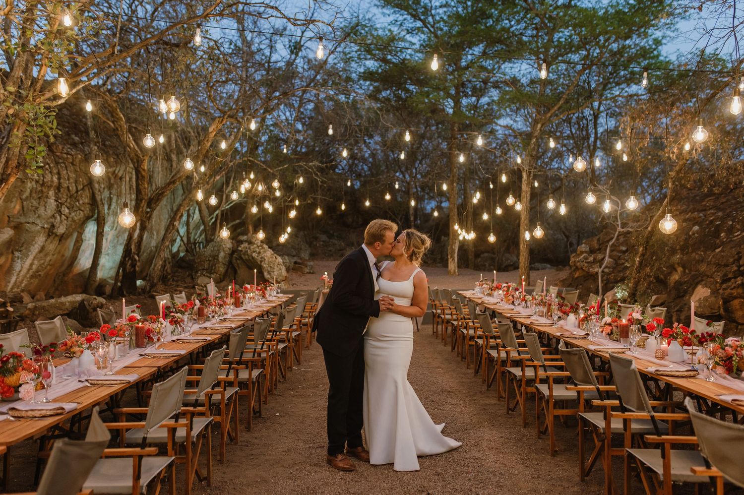 A beautifully decorated outdoor wedding reception with string lights and red accents.