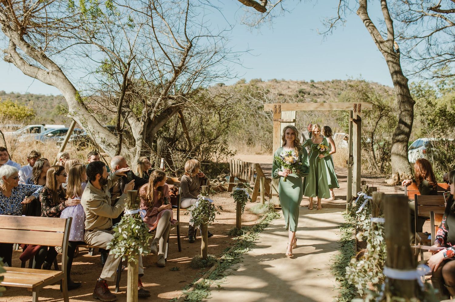 Outdoor wedding ceremony setup with wooden chairs and natural desert landscape backdrop.