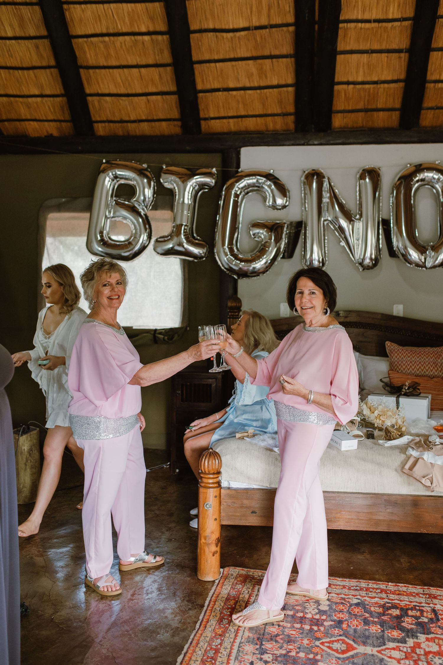 Wedding party in pink robes dancing and celebrating in rustic venue.