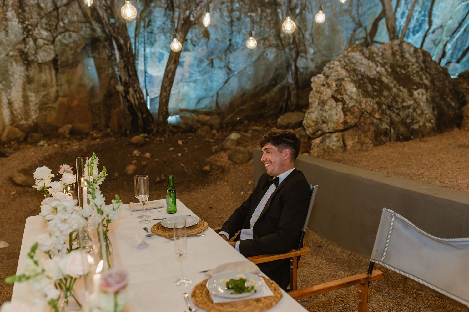 Wedding reception dining tables arranged outdoors with elegant white table settings.