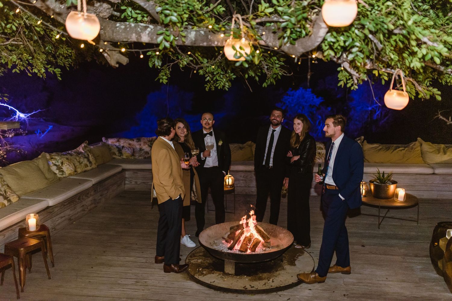 Outdoor wedding venue decorated with hanging lanterns and greenery creating a romantic evening atmosphere.