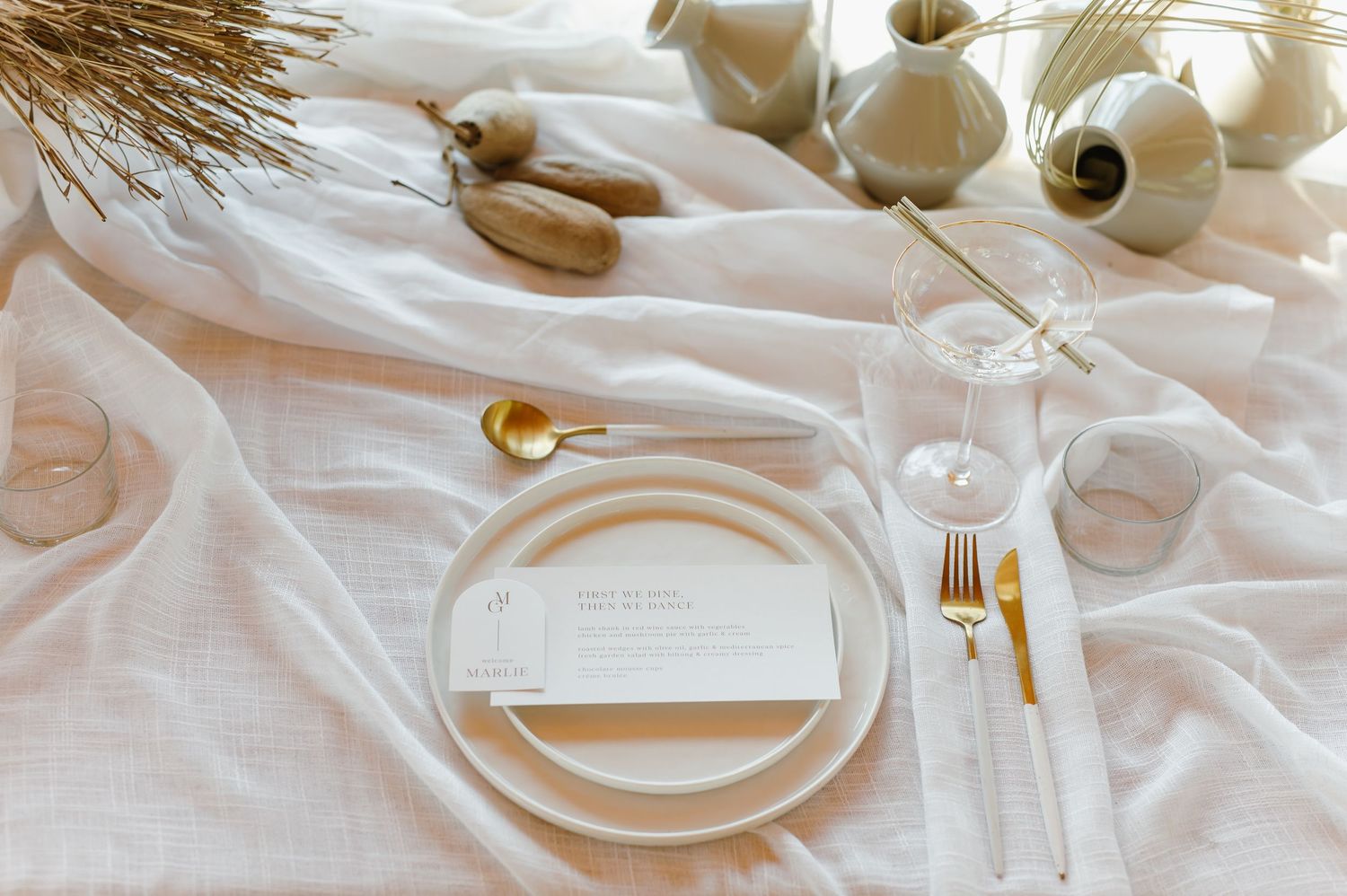 Elegant white table settings with gold accents and crystal glassware arranged for a formal event.