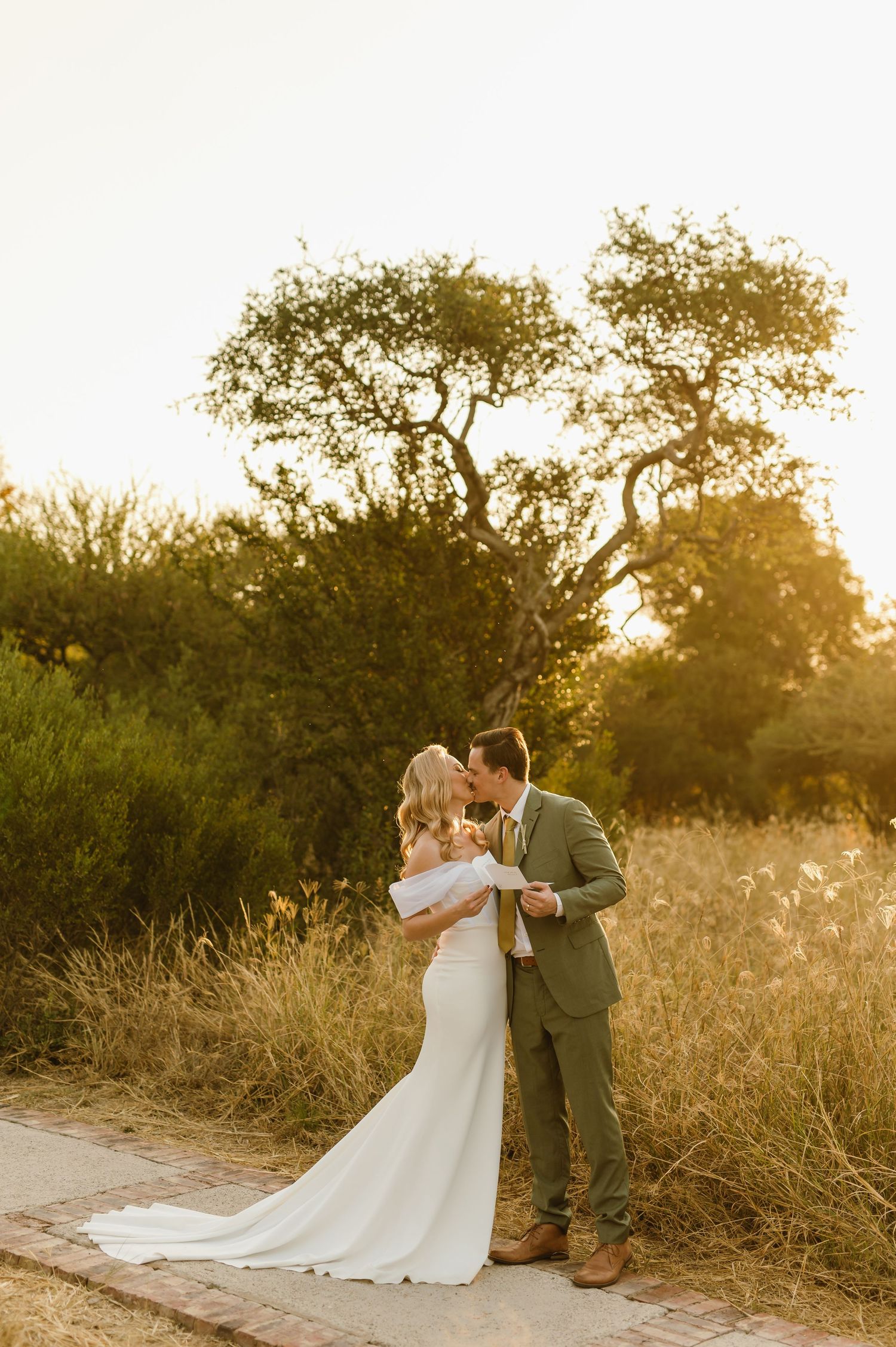 Newlyweds sharing an intimate moment on a trail surrounded by golden sunlit trees.