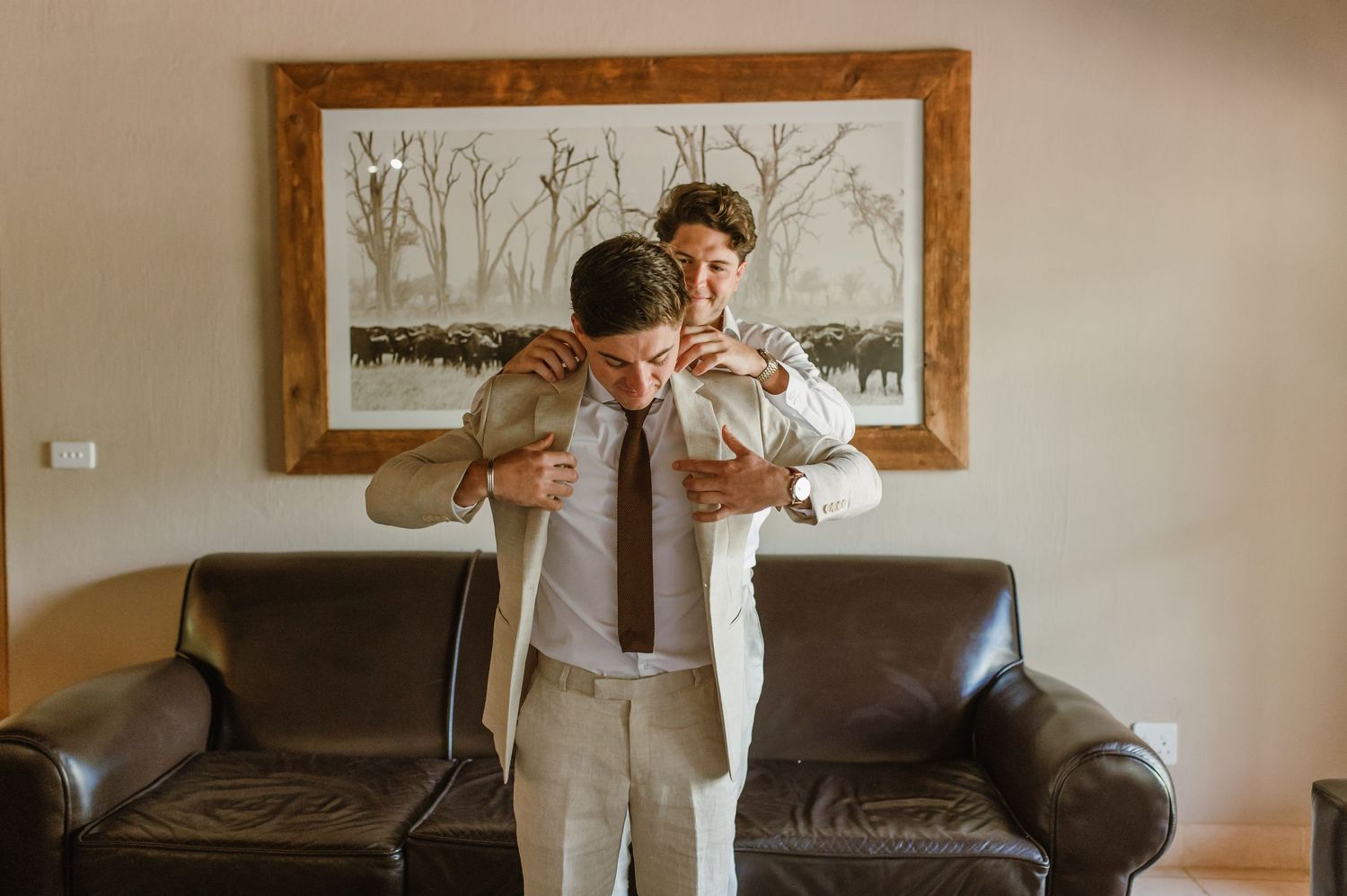 Multiple angles of someone getting dressed in formal attire against a wall with framed artwork.