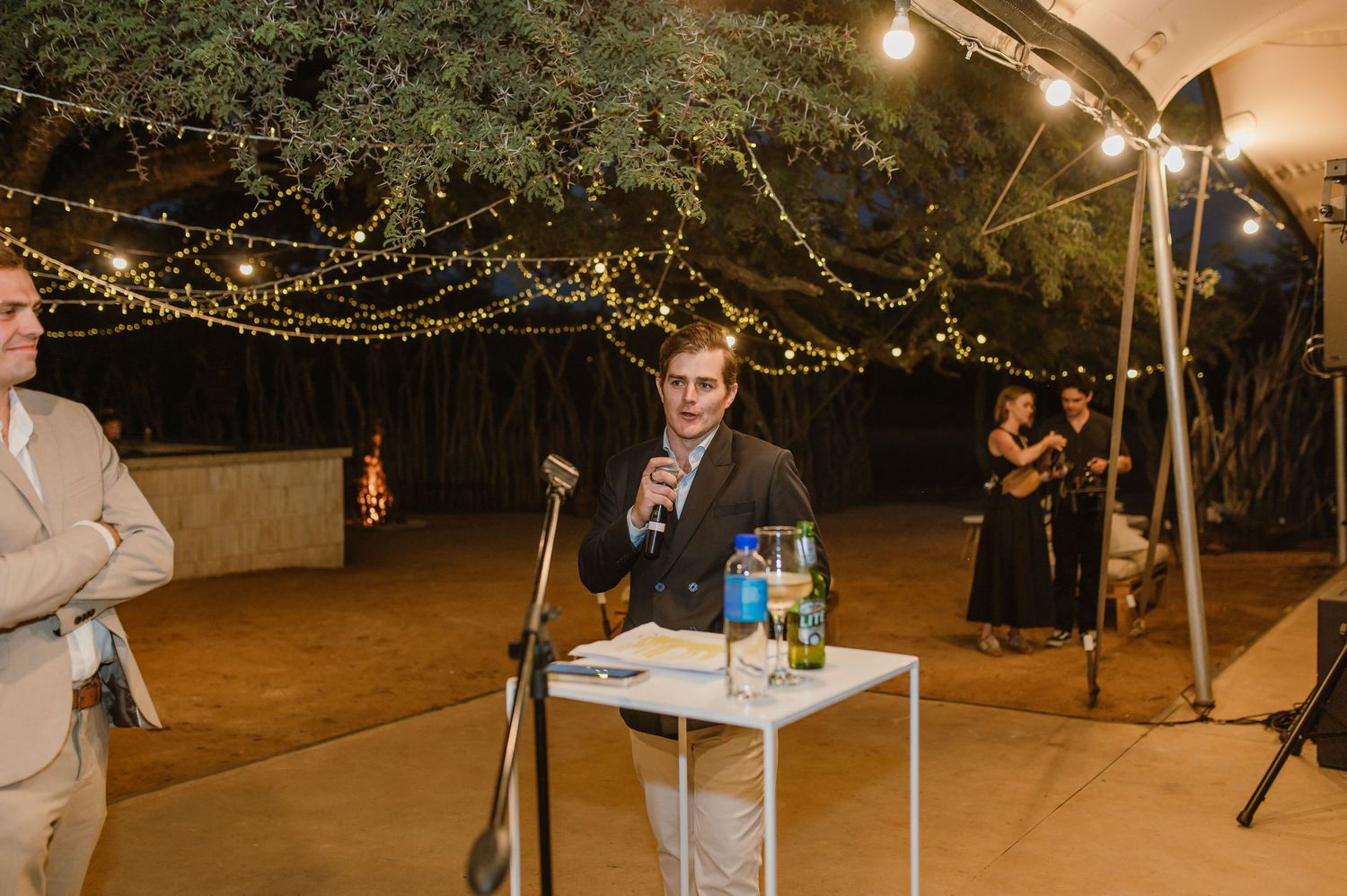 String lights illuminate an outdoor wedding venue at night.