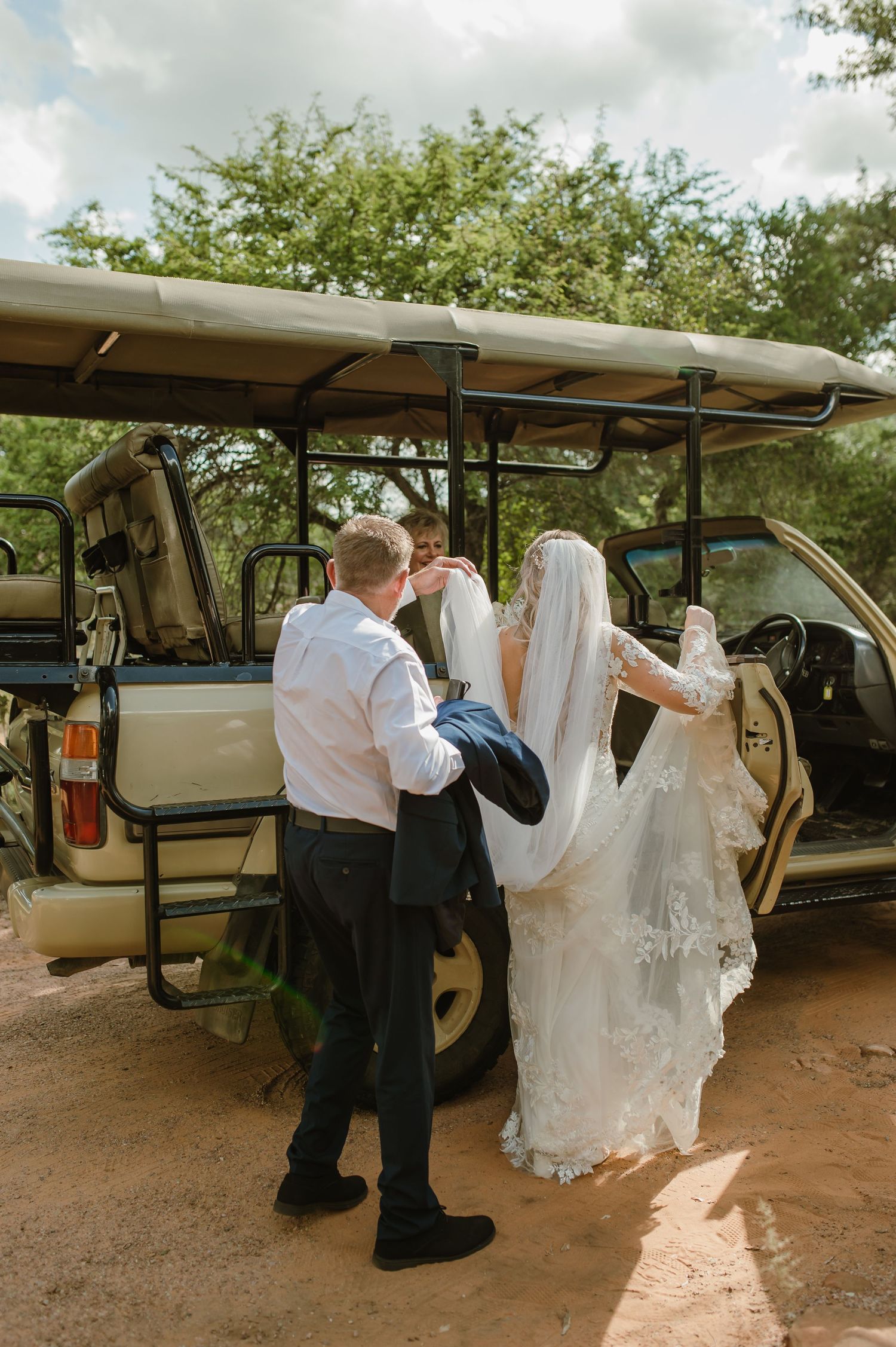 Wedding party preparing to board safari vehicles at outdoor venue.