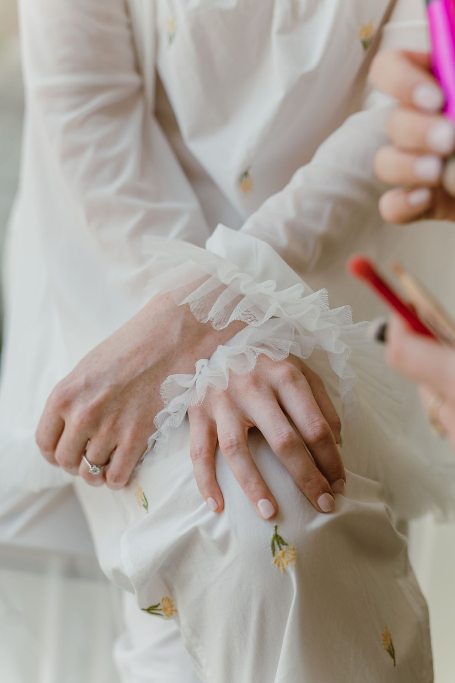 Close-up of hands adjusting delicate white ruffled fabric details.