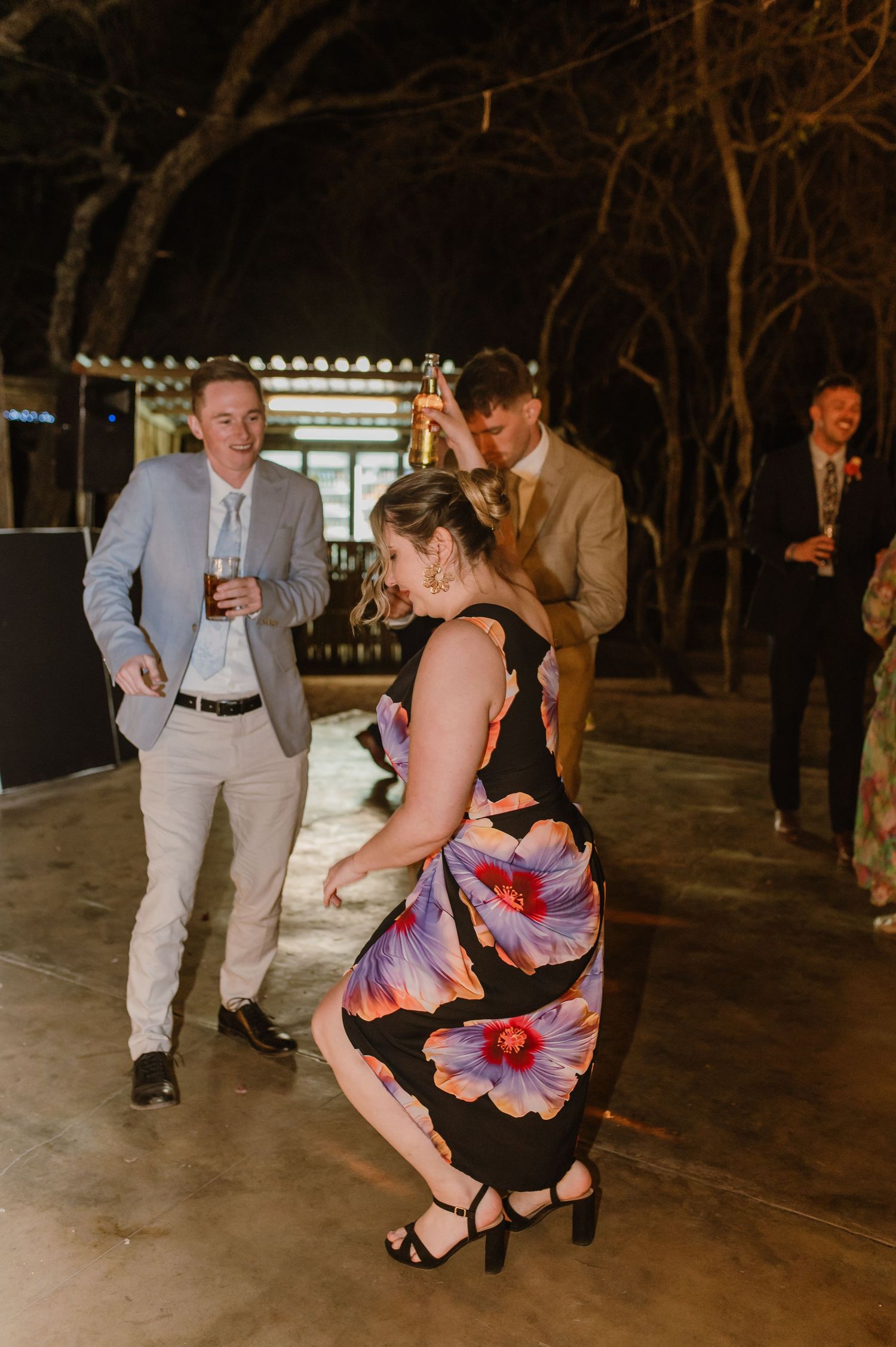 Guests dancing energetically on a concrete floor at a rustic wedding reception.