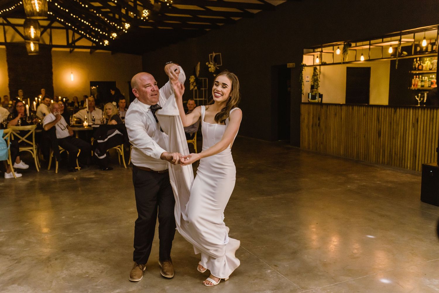 A couple dances together during their wedding reception in an elegant venue.