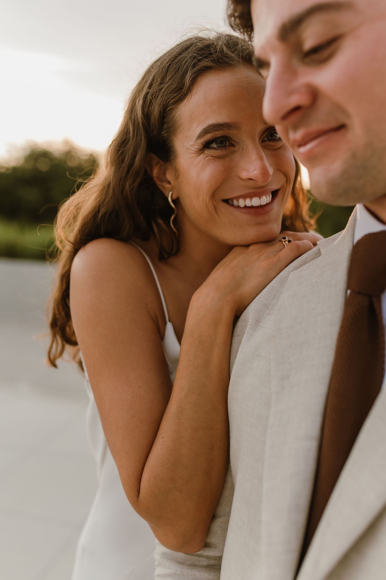 A close-up candid moment of a couple in wedding attire during sunset.
