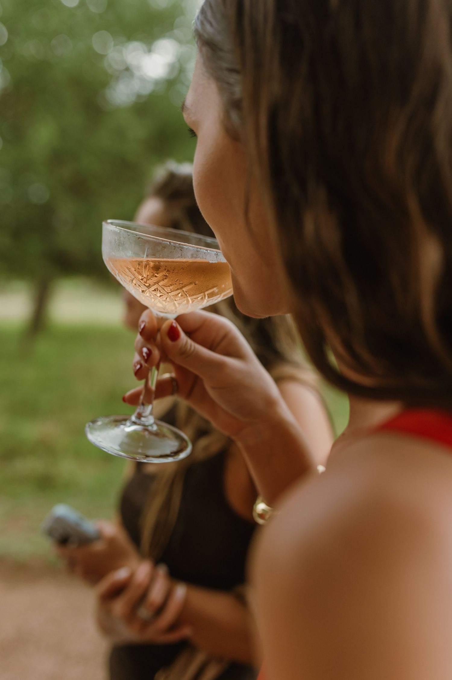 Close-up of champagne glasses being held during outdoor wedding celebration.