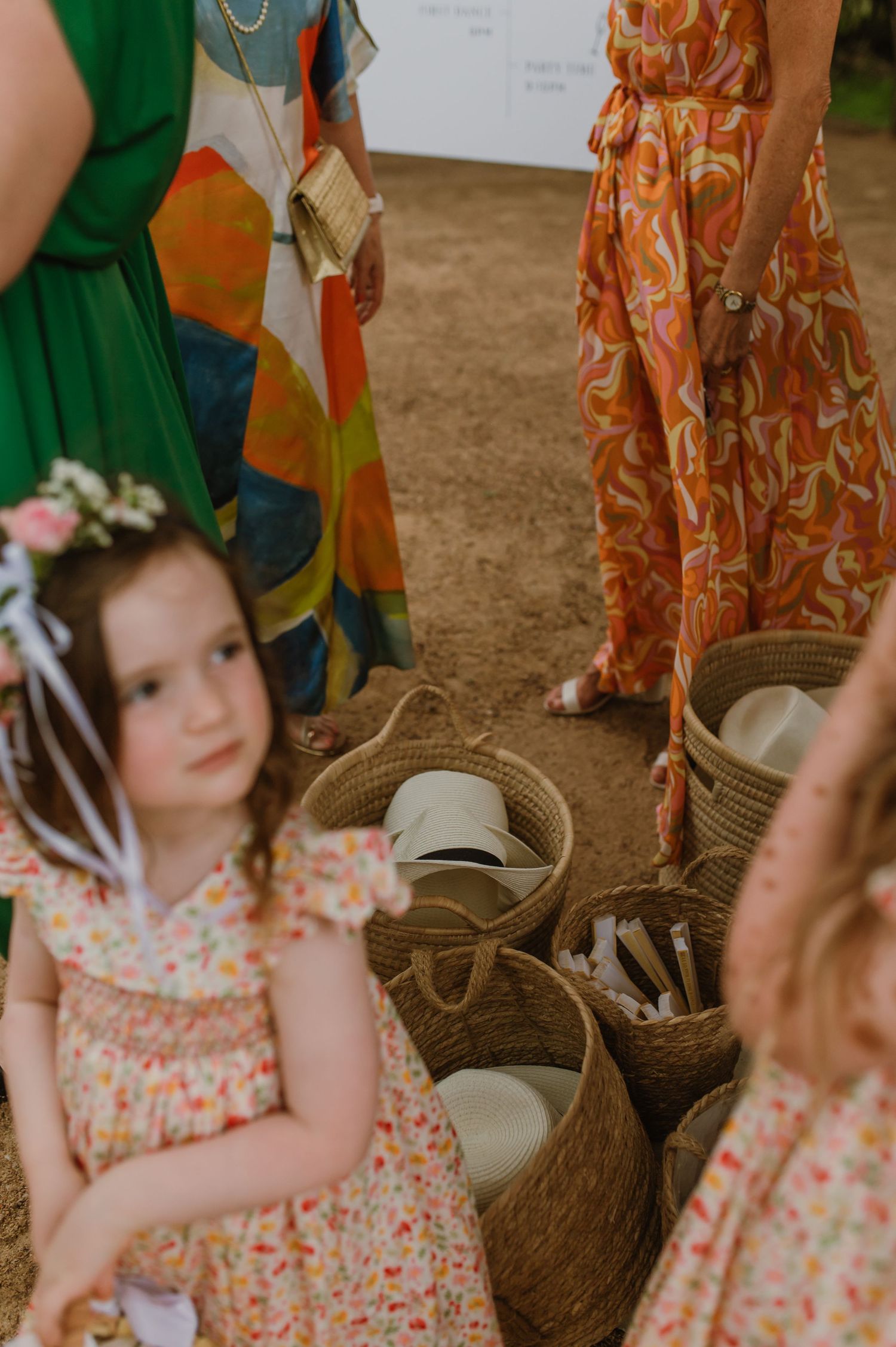 Young attendees in floral dresses at a rustic outdoor wedding celebration.