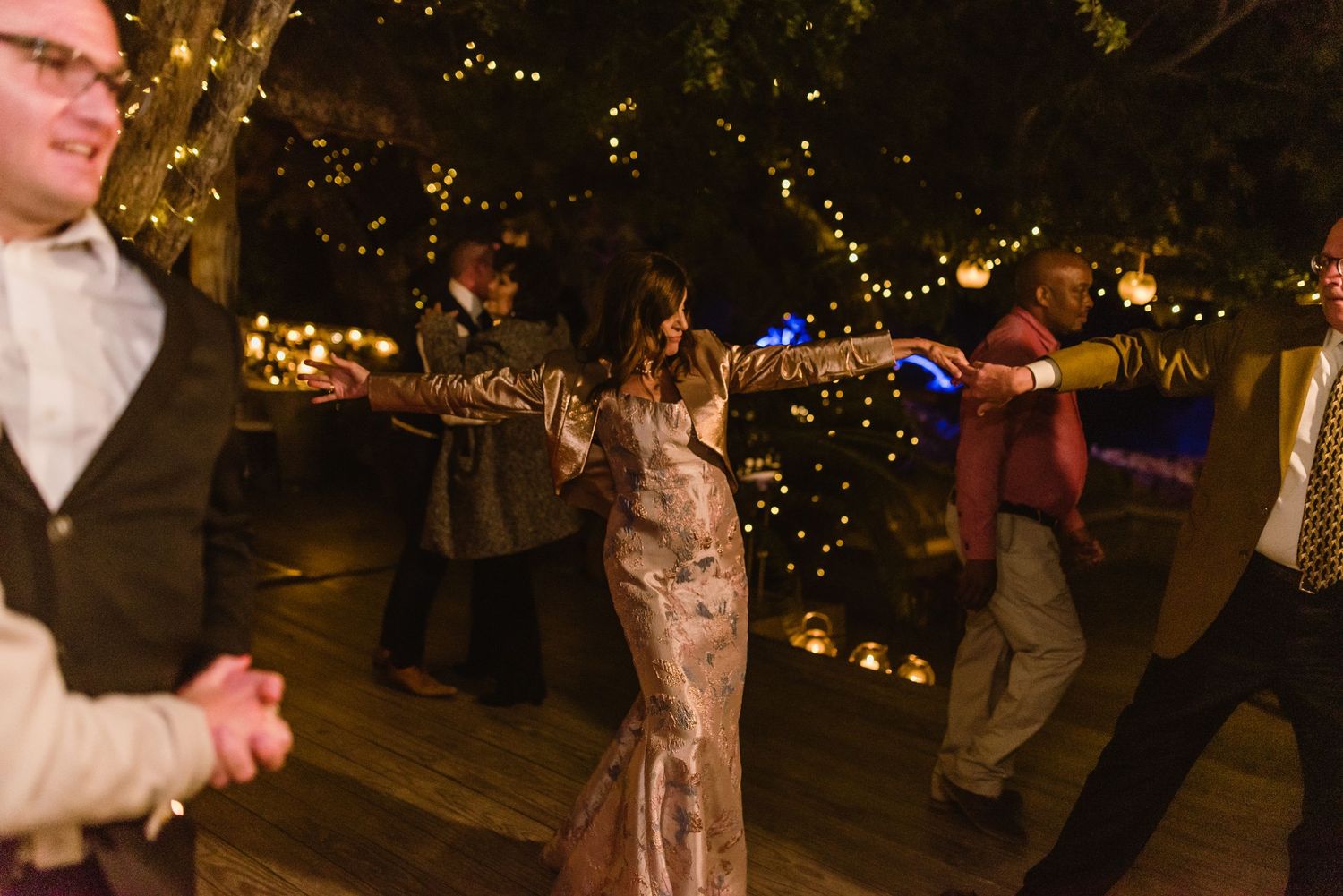 Wedding reception guests dancing under twinkling lights in a rustic barn setting.