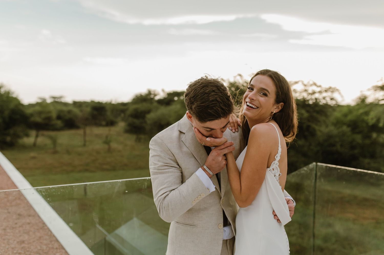 A romantic couple embraces in an outdoor field during sunset creating an intimate silhouette against the golden sky.