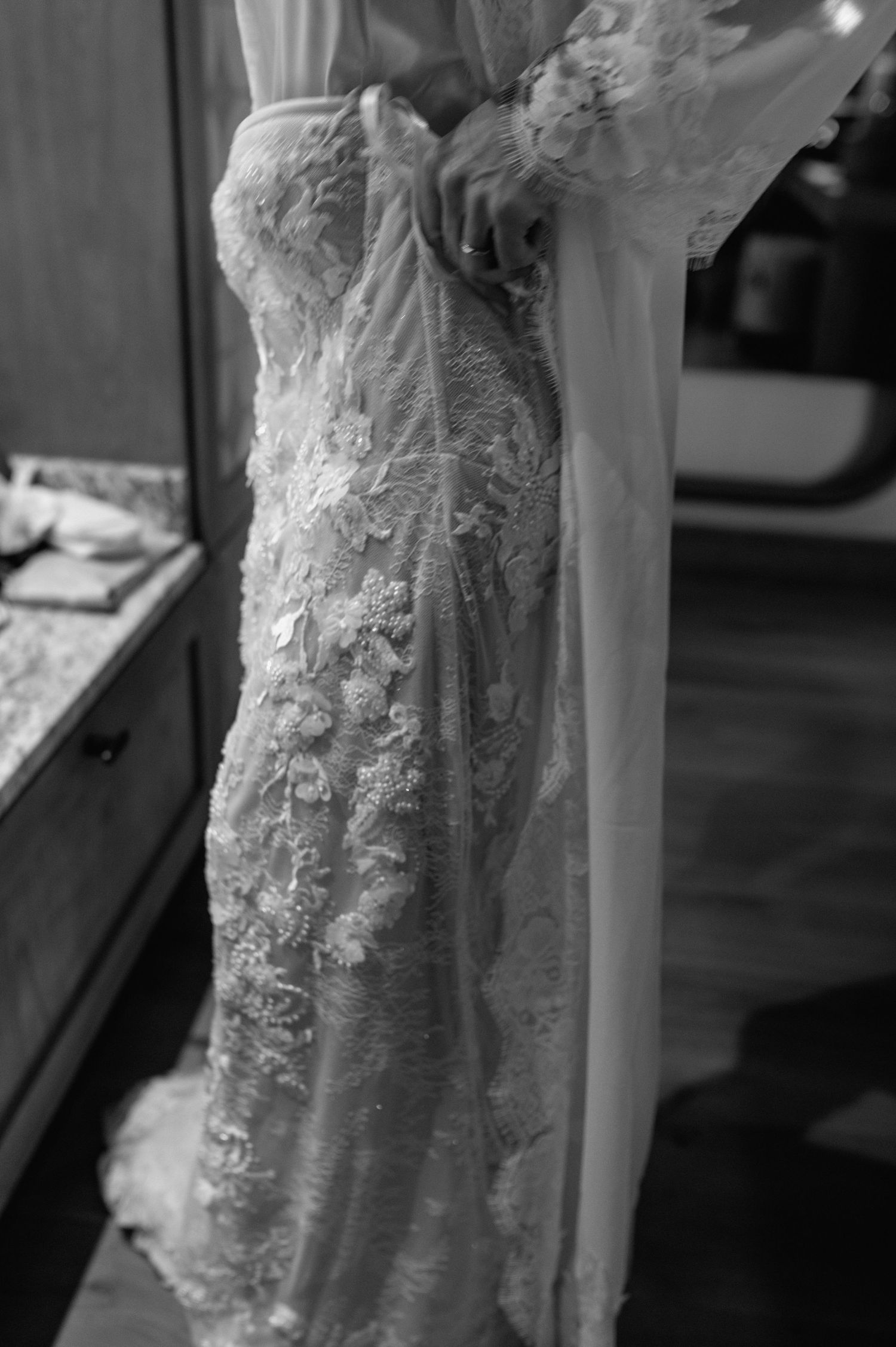 Black and white close-up of a bride in a strapless floral lace wedding gown.