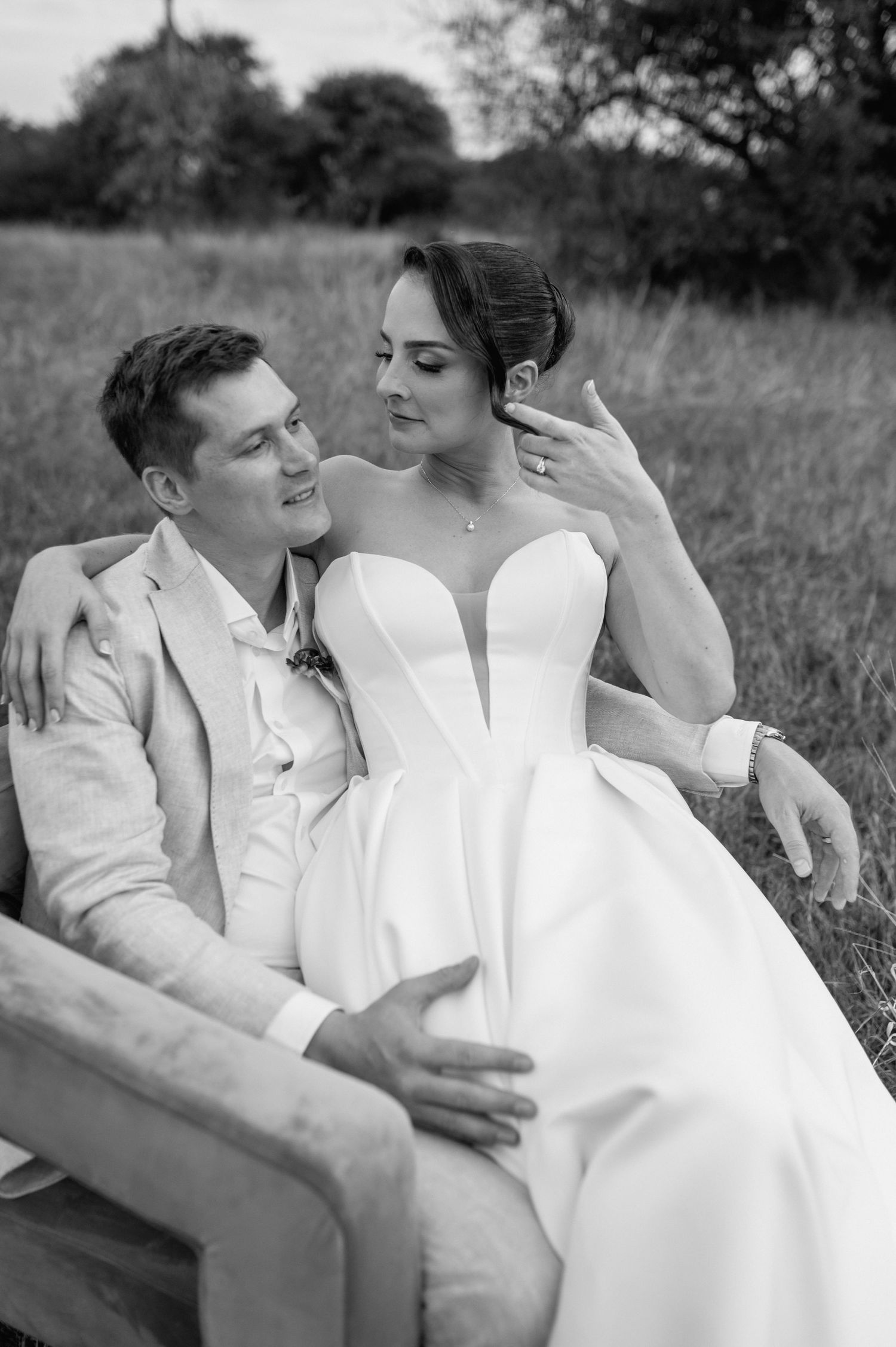 Black and white romantic couple portrait series showing tender moments while lying in a grassy field.