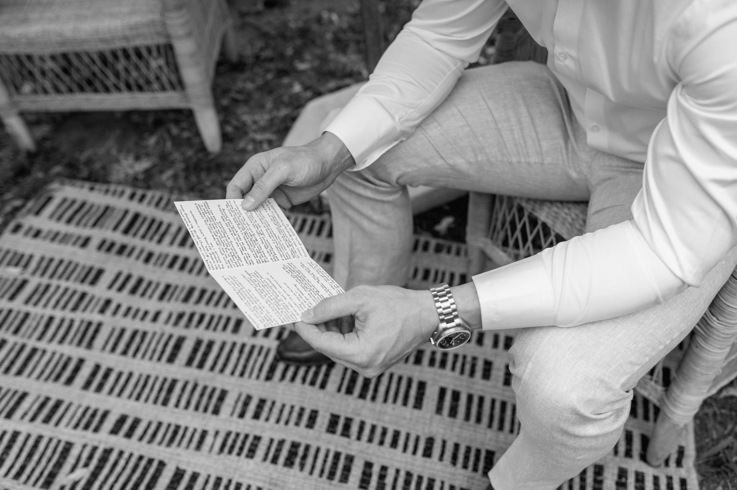 A person in white attire sorting through paper documents on a desk in a black and white photograph.
