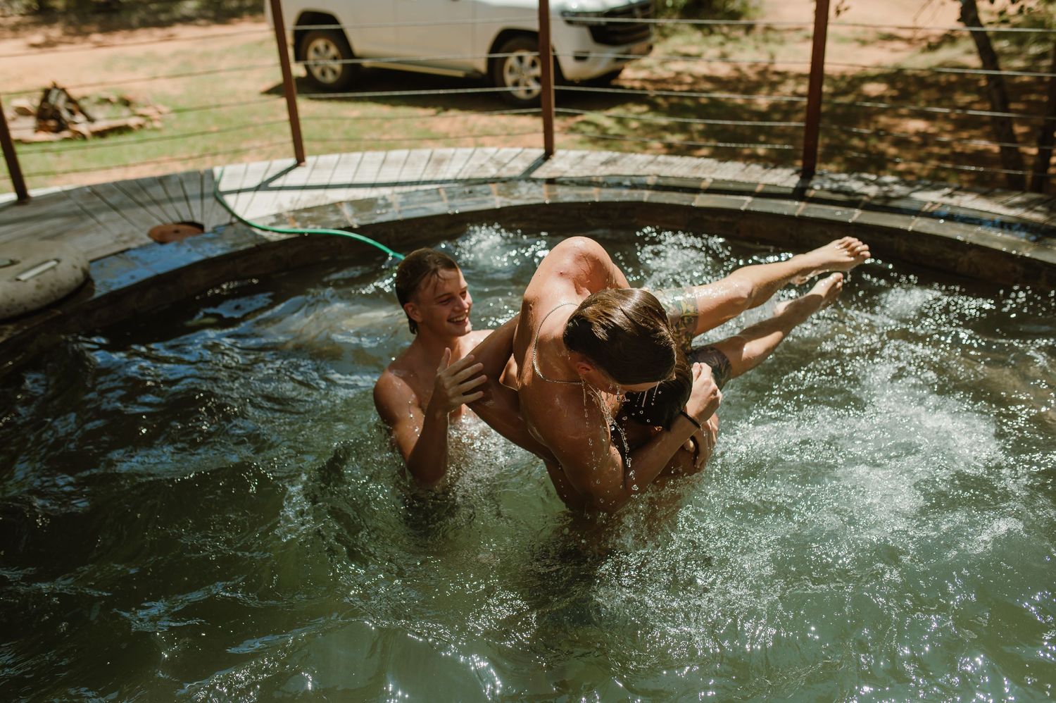 People splashing and playing in a crystal clear swimming pool on a sunny day.