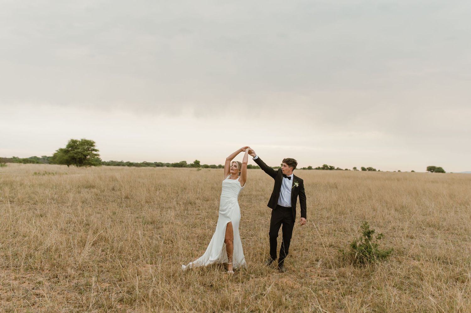 Wide landscape wedding shots showing couple in vast prairie field.