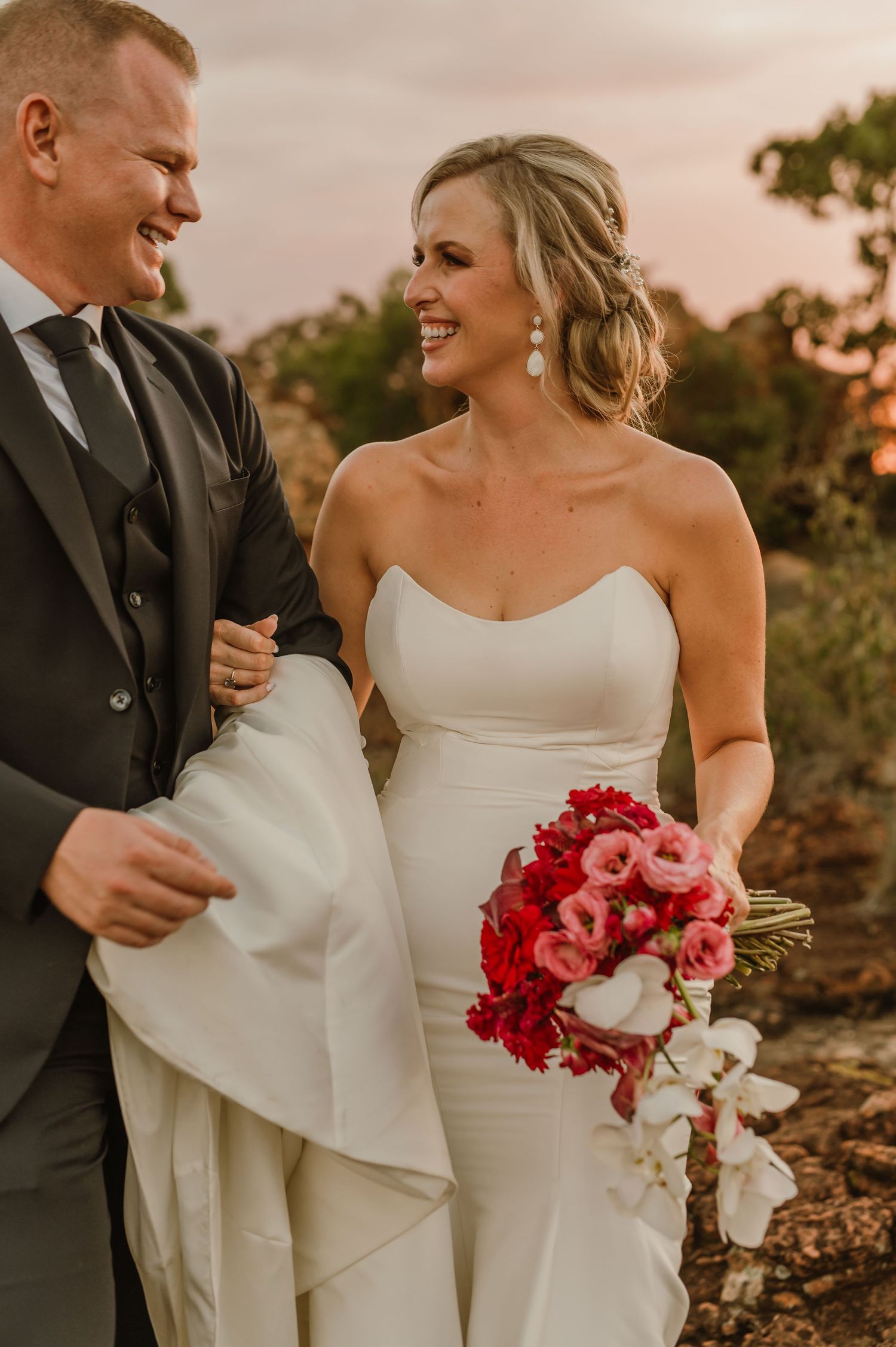 Candid wedding portraits showing tender moments between newlyweds with pink and red floral bouquet.