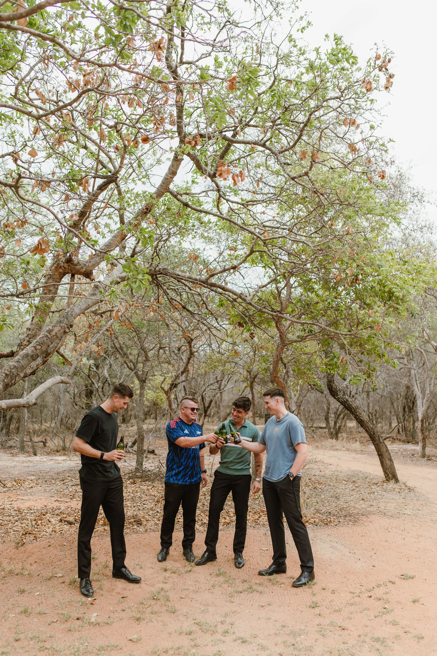 A group stands together under trees in a natural outdoor setting during a casual gathering.
