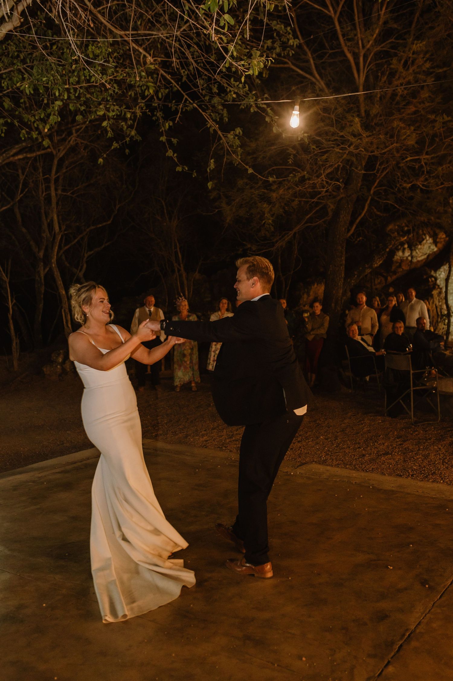 Couples dancing on an outdoor patio under warm evening lights.