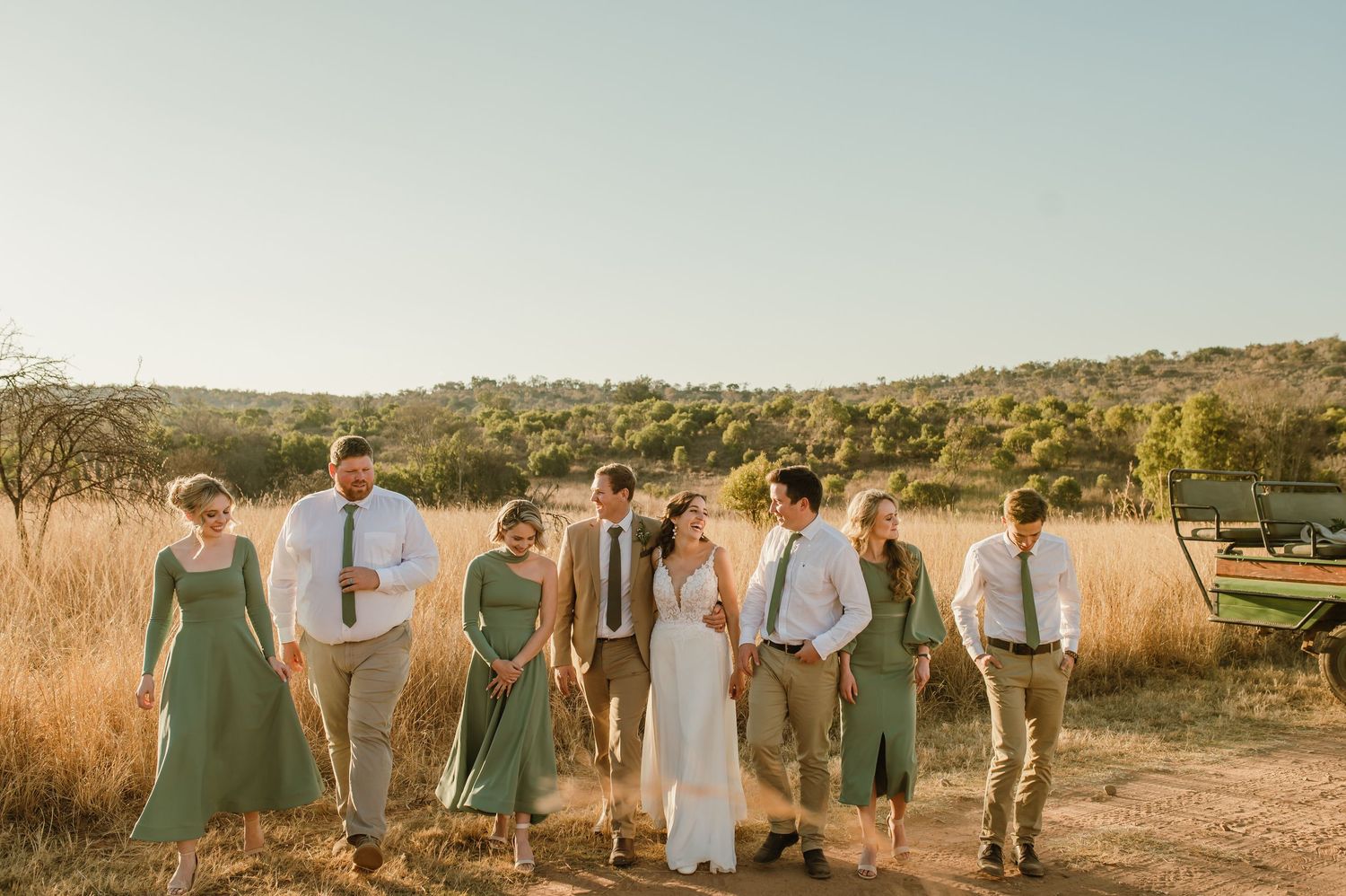 Wedding party gathered in a desert setting with natural grass and mountain backdrop.