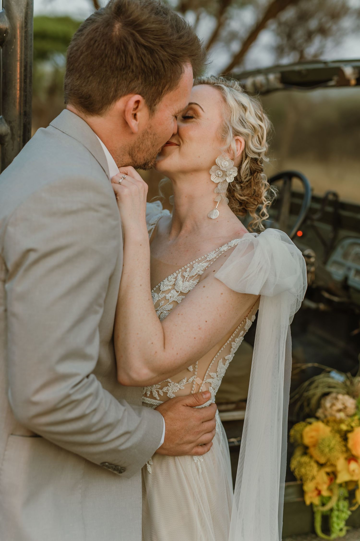 Romantic wedding portraits showing tender moments between newlyweds near vintage vehicle.