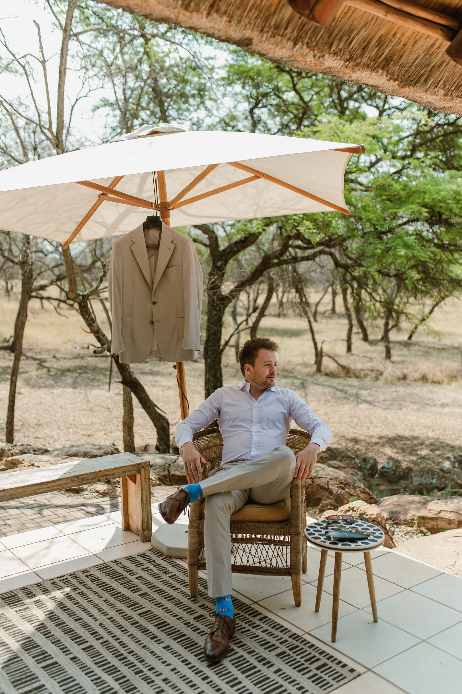 Person in formal attire lounging on a patio with umbrella shade.
