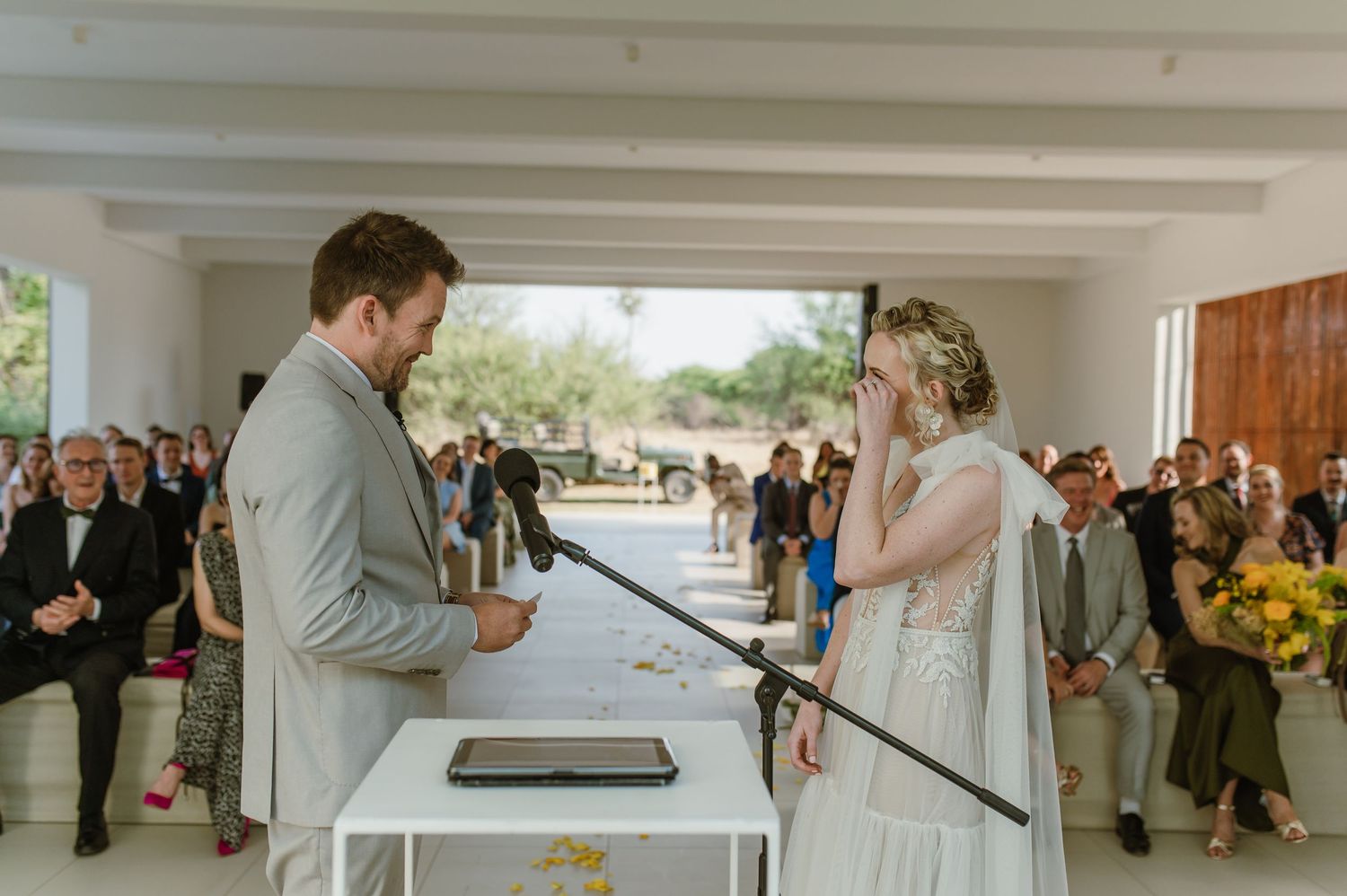 Wedding ceremony in progress in a minimalist white room with natural lighting.