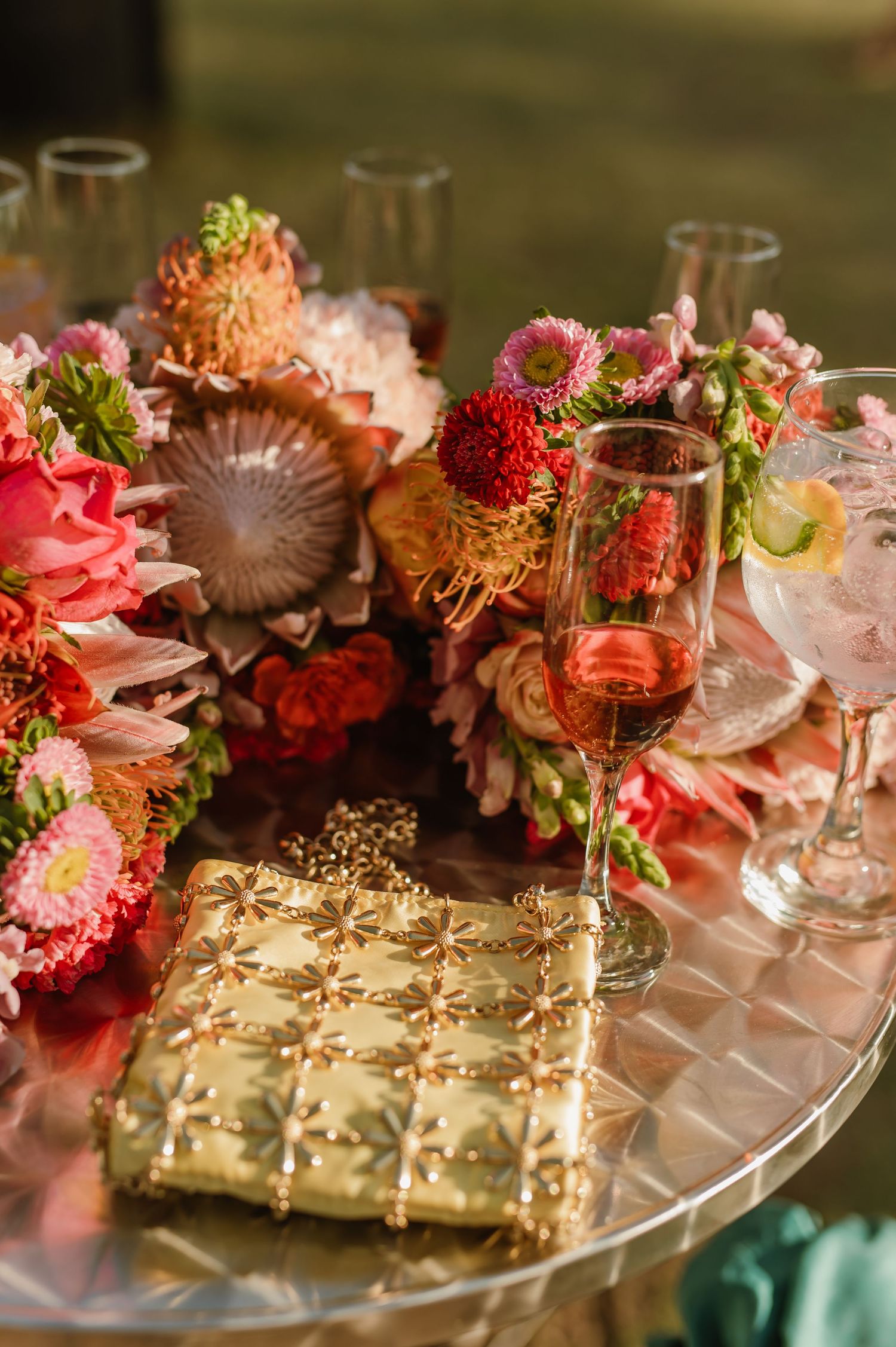 Elegant table decor features pink and red flowers with gold accents on a glass surface.