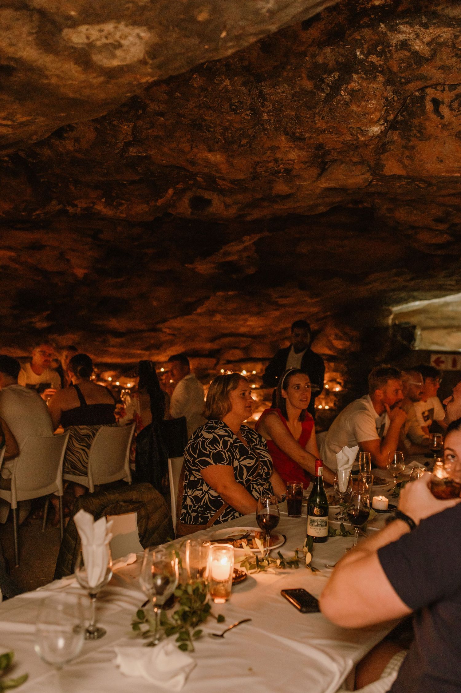 Guests dining at candlelit tables in an atmospheric cave restaurant.