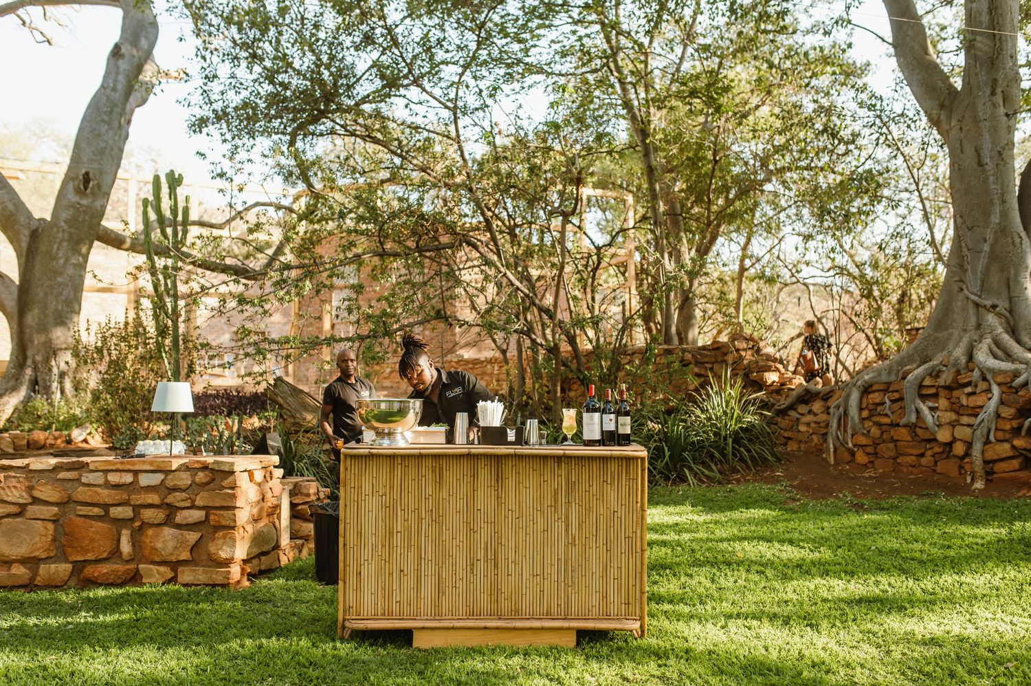 Outdoor wedding venue setup with wooden furniture and natural decor among trees.