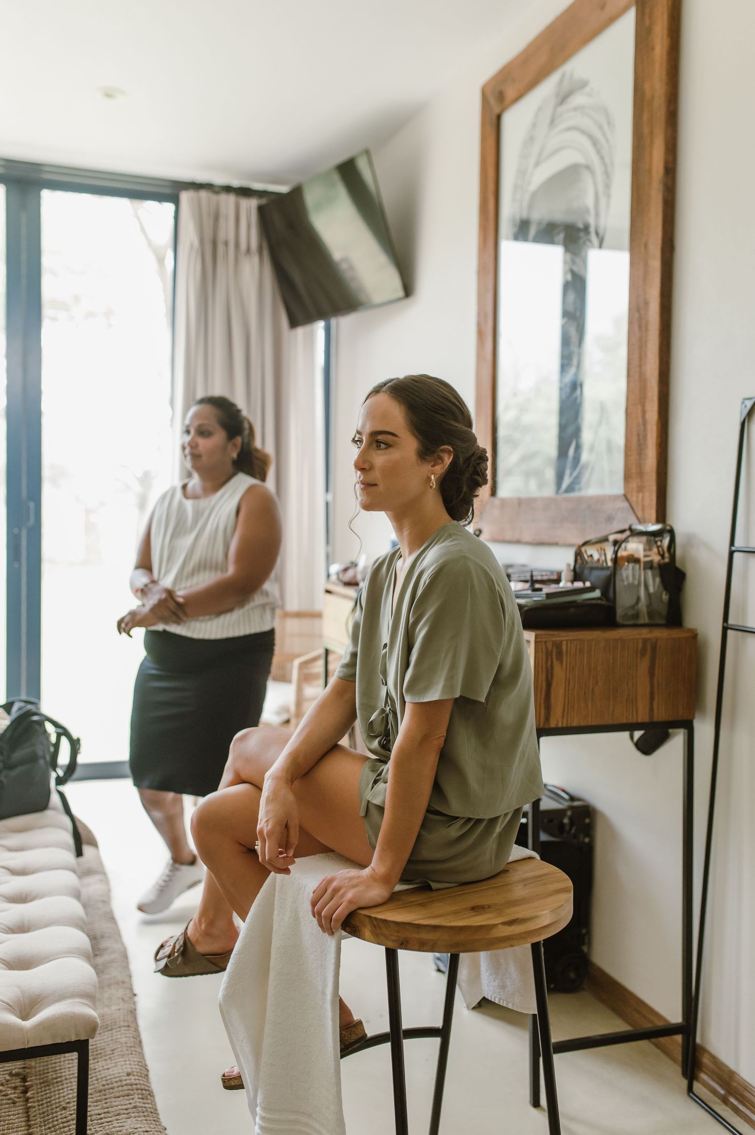 Bridal party getting ready in a bright room with wooden framed mirrors.