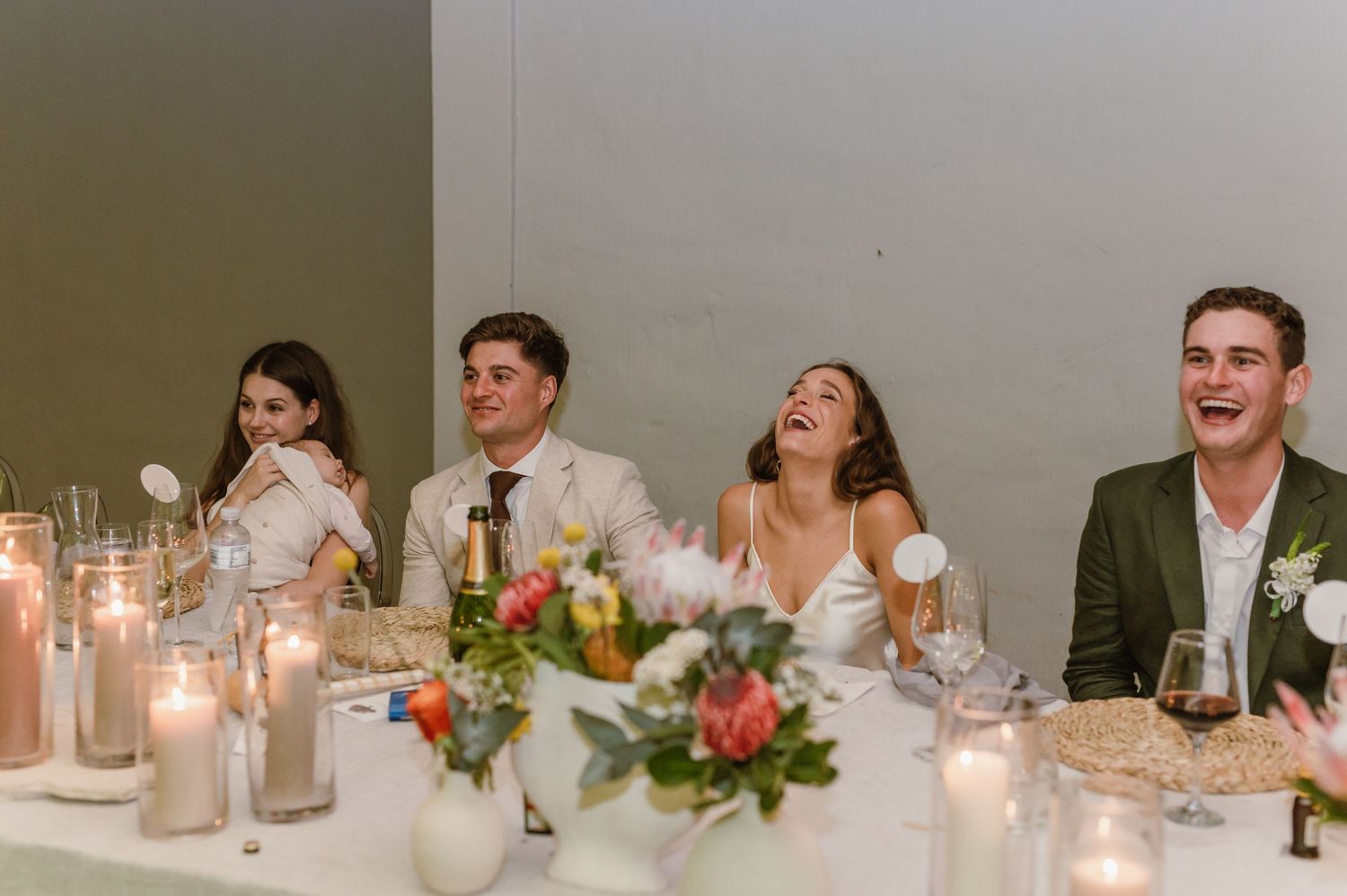 Wedding reception dinner tables set with candles and floral centerpieces in elegant white decor.