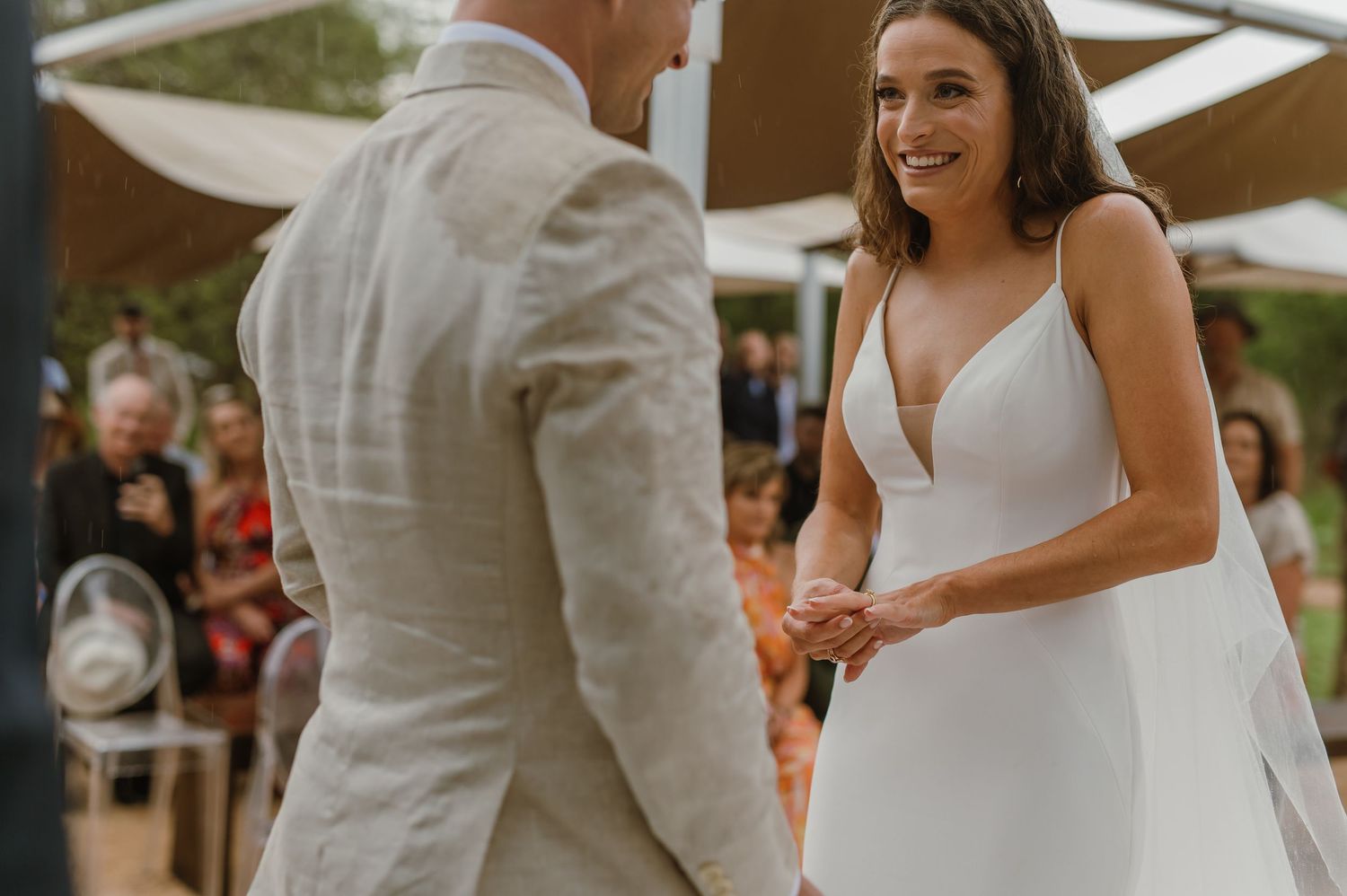 A couple shares a joyful moment during their wedding ceremony under a rustic outdoor setting.