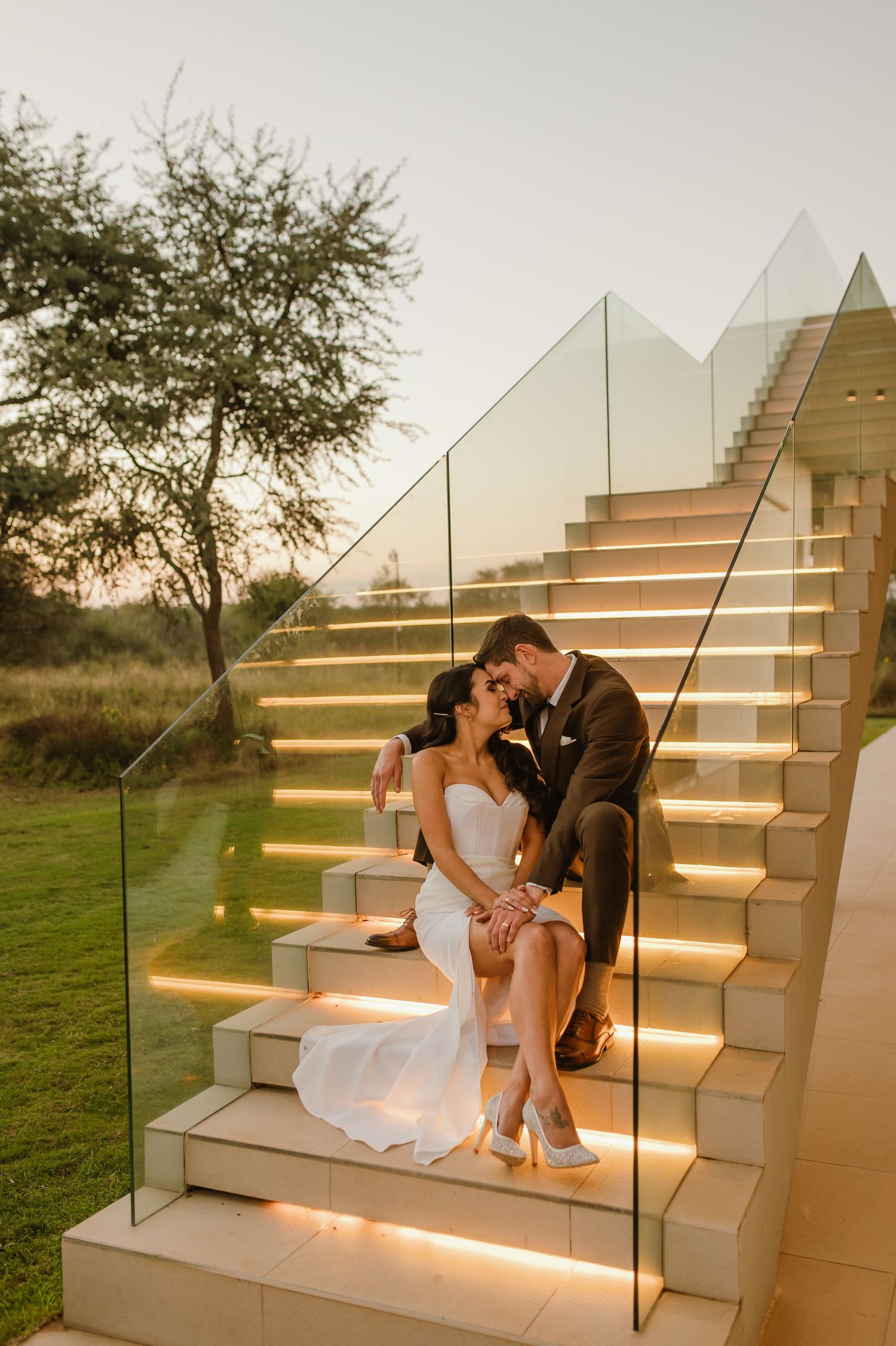 A couple sits romantically on illuminated outdoor stairs at dusk.