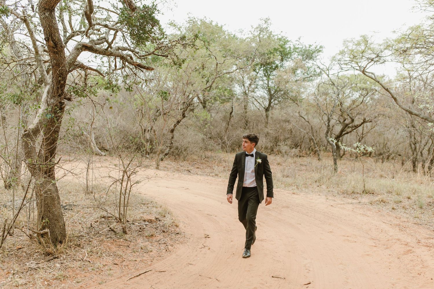 Walking shot on a dirt path through trees wearing classic black tie attire.
