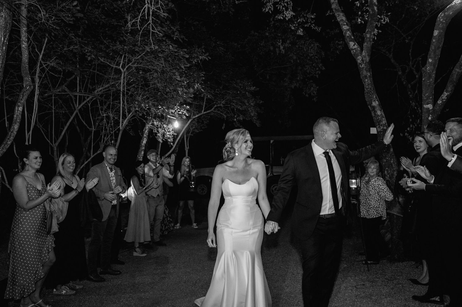 Black and white photo of guests dancing and celebrating at an outdoor evening event.