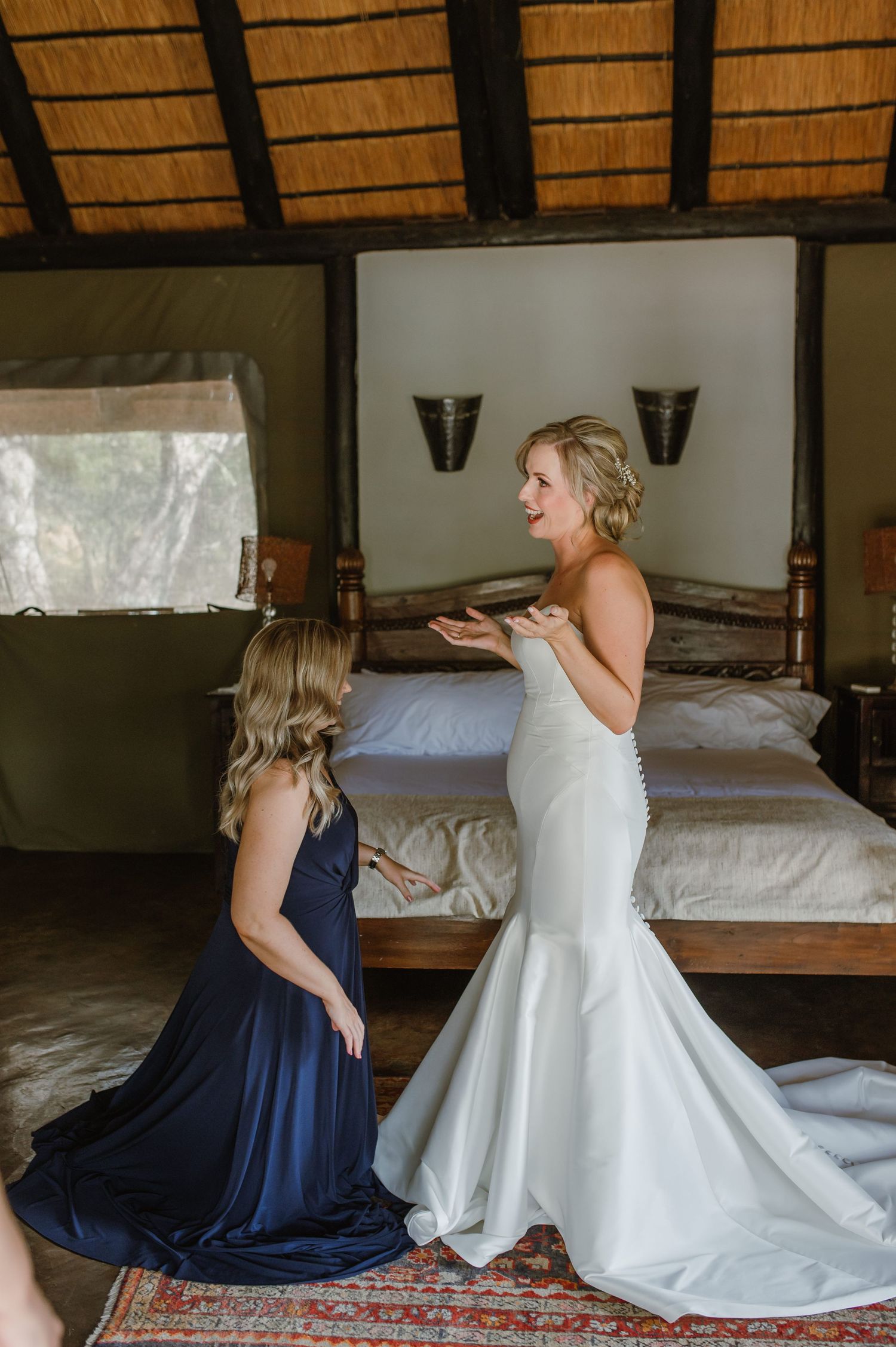 Wedding dress preparation with navy blue bridesmaid dress in rustic lodge setting.
