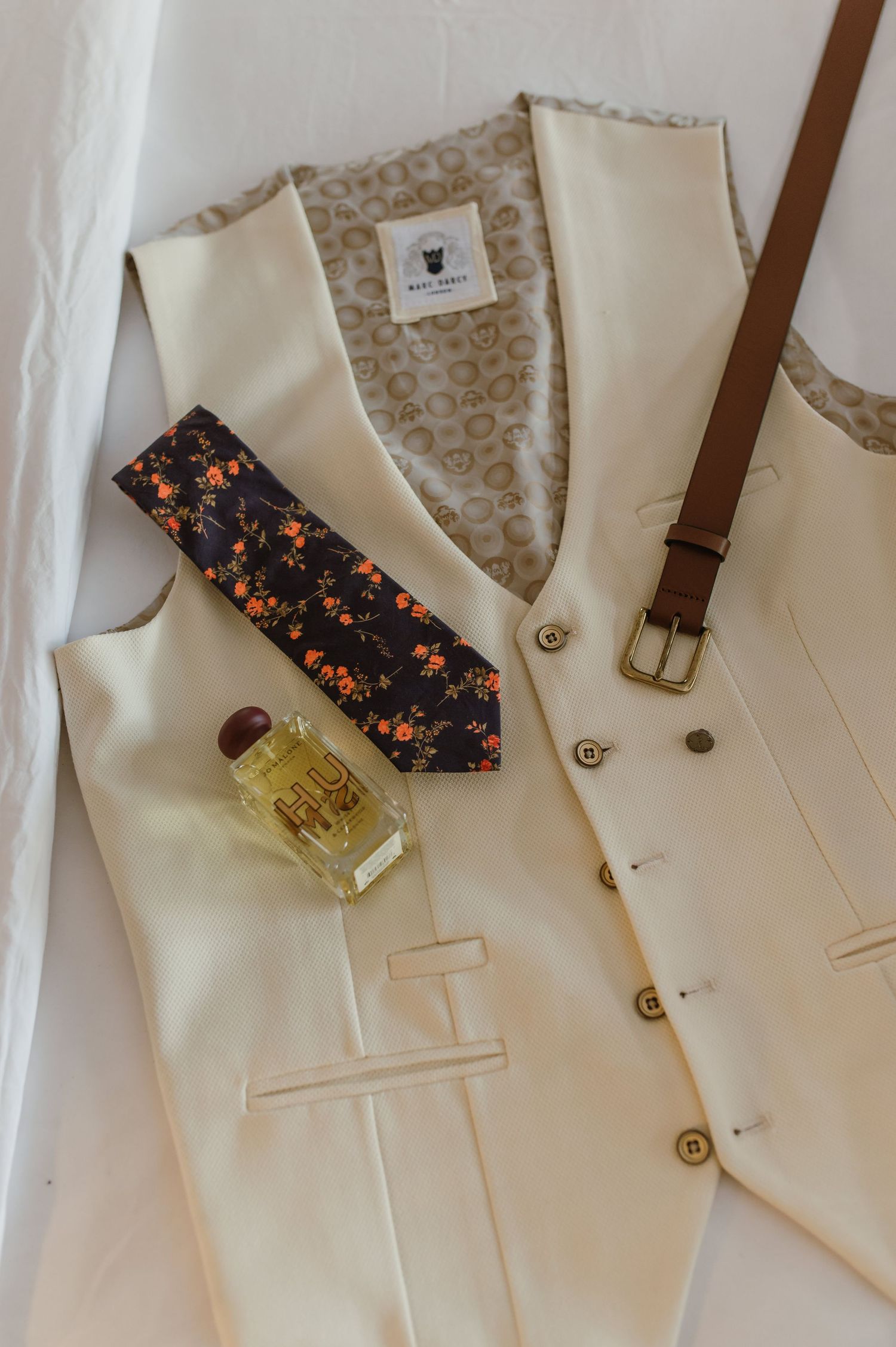 Cream colored formal vests with floral ties laid out for a special occasion.
