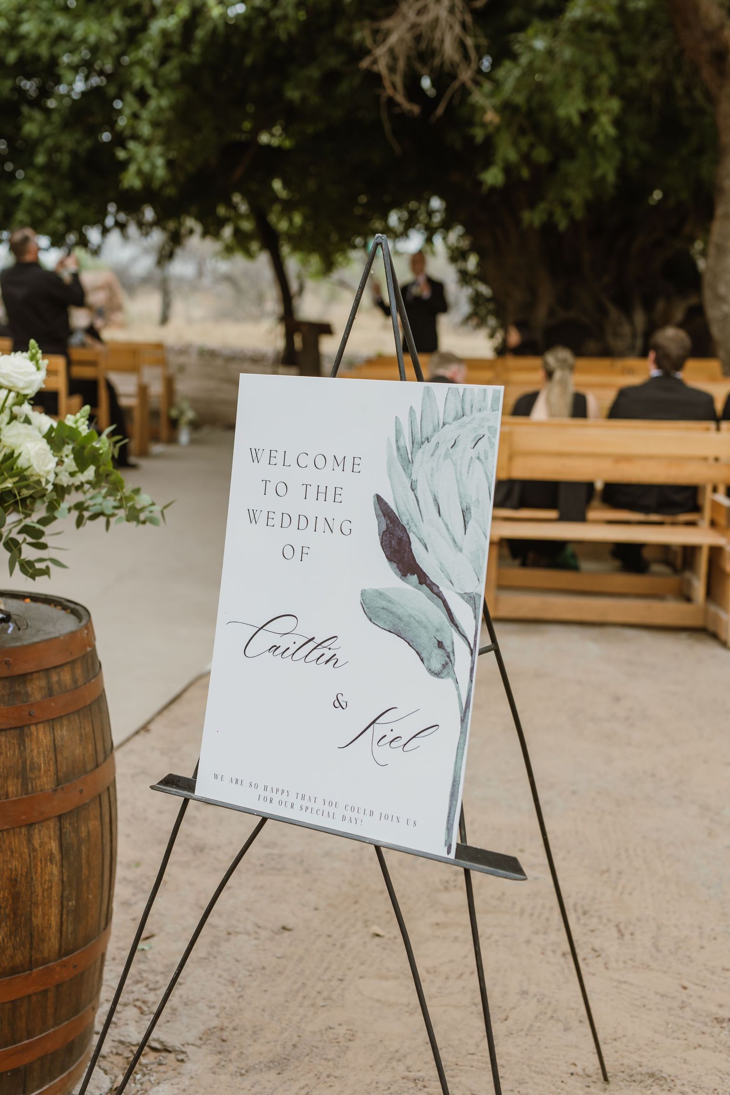 Wedding welcome sign on an easel with rustic barrel decor.