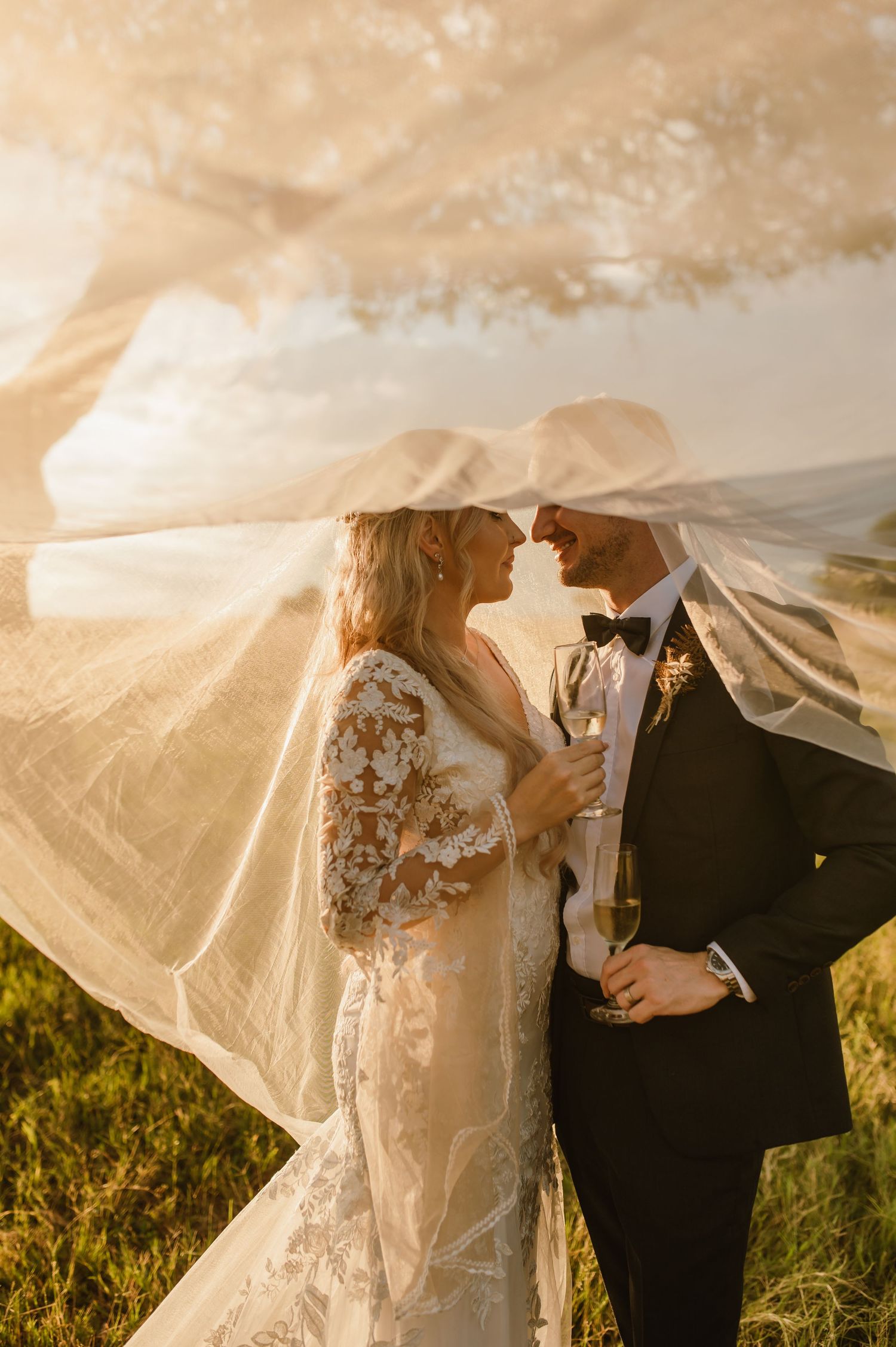 A romantic wedding portrait with flowing veil captures the couple in golden sunlight.