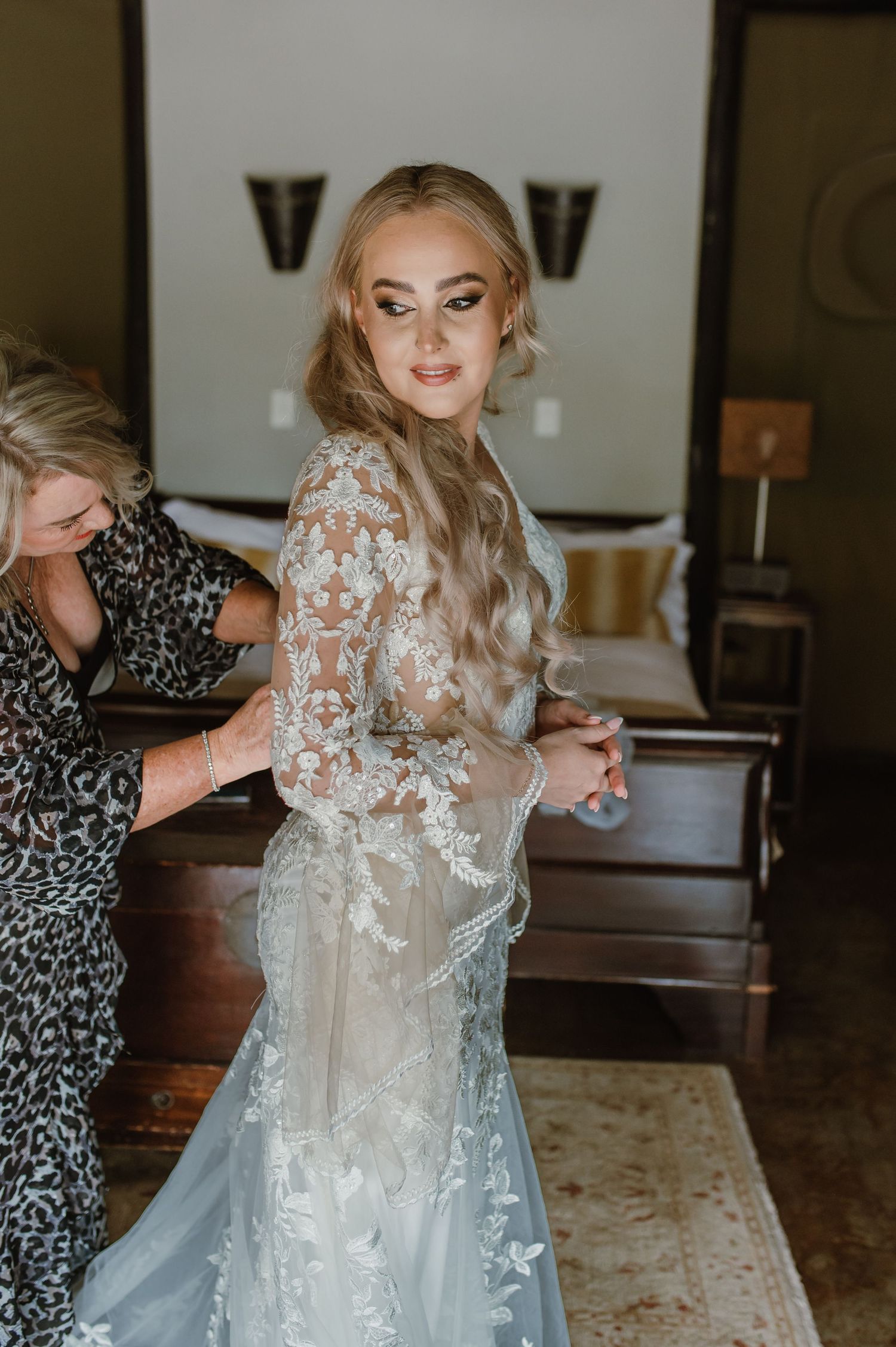 A wedding dress with delicate floral lace appliques being prepared for the bride.