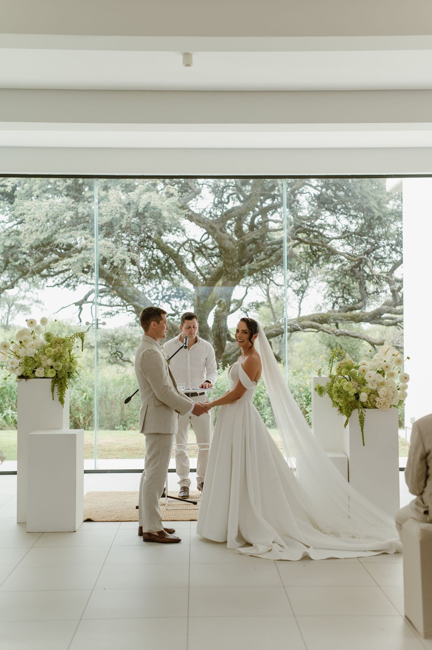 Modern minimalist white wedding venue with floor-to-ceiling windows overlooking nature.