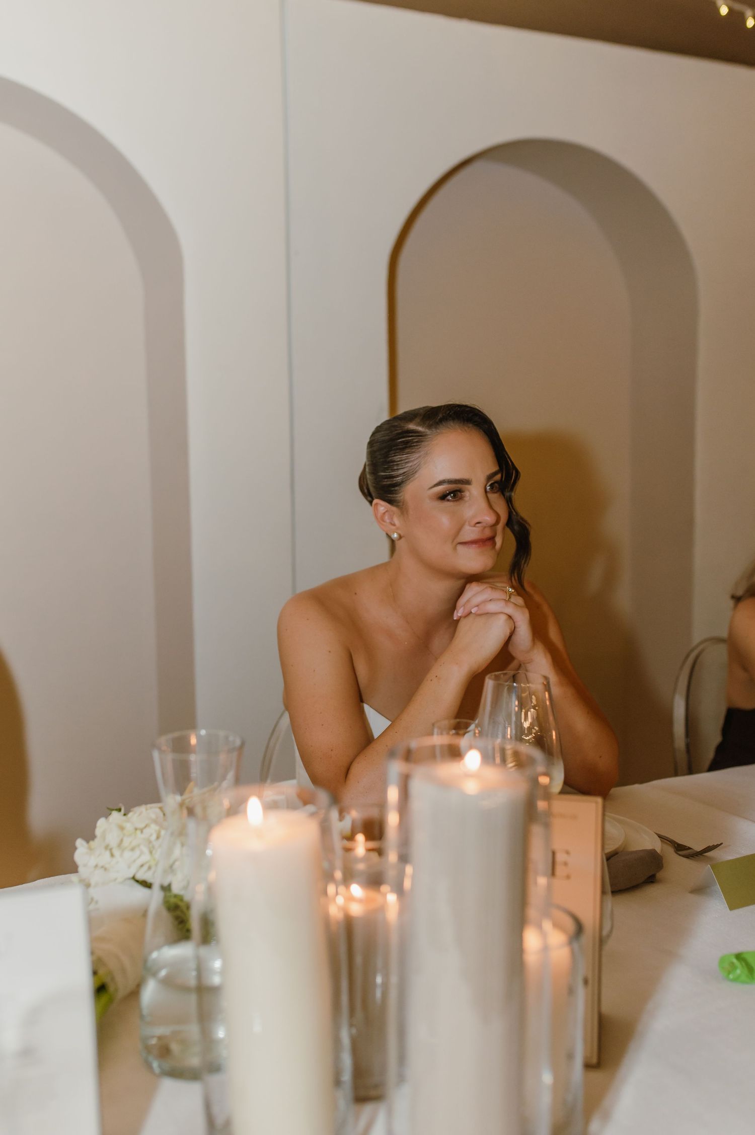Intimate wedding reception table setting with glowing candles and white floral arrangements.