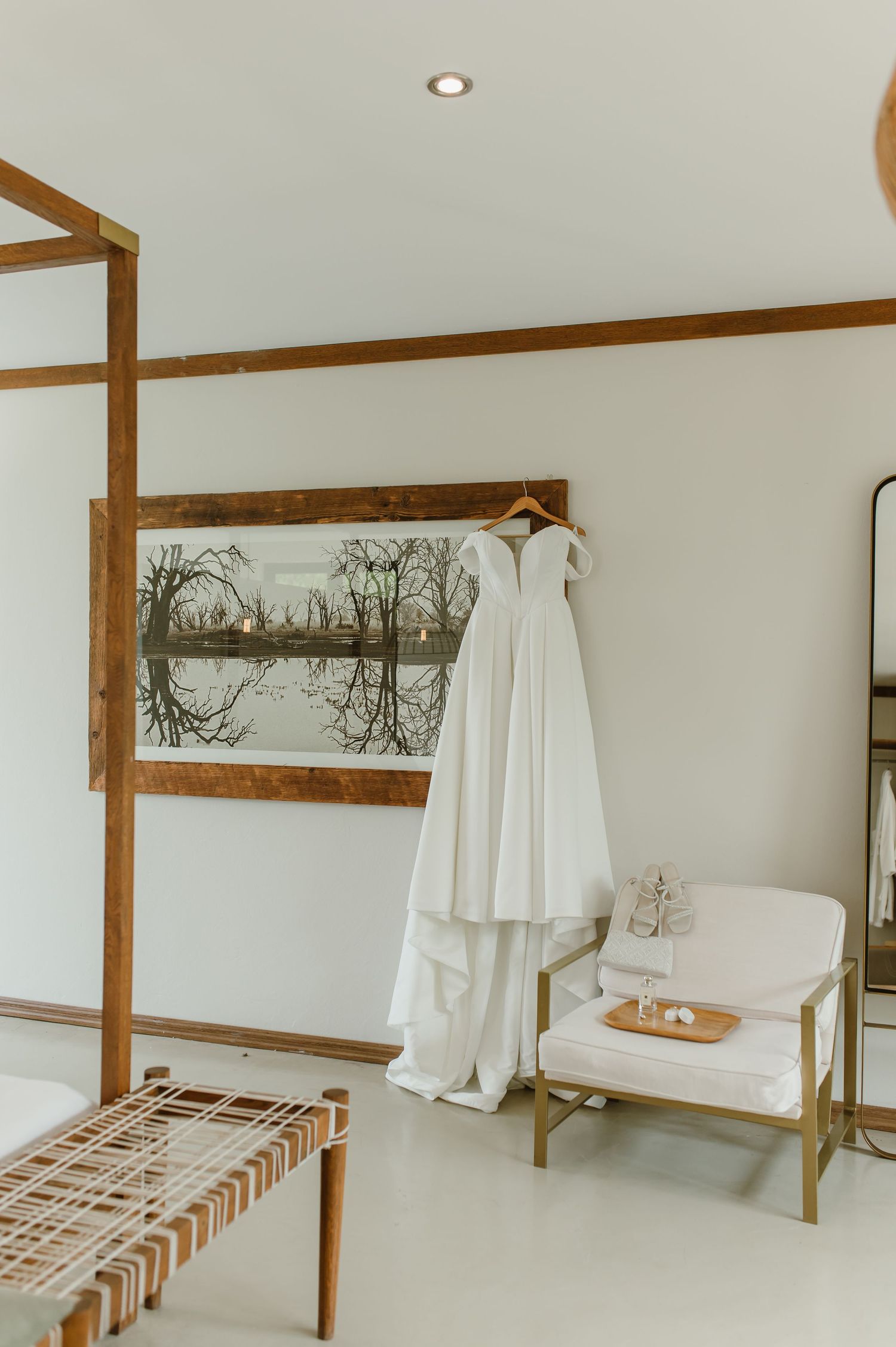 Minimalist spa-like bathroom interior with wooden beams, white walls, and hanging robes against a serene backdrop.