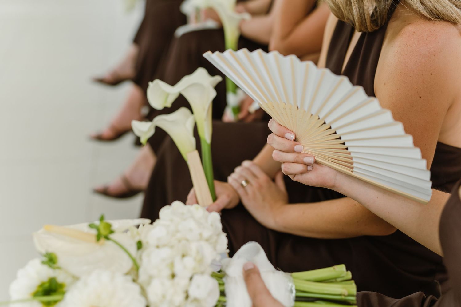 White paper fans and floral bouquets displayed at an elegant wedding ceremony.