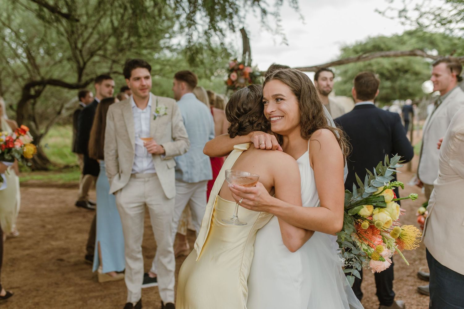 Wedding party members celebrating outdoors with drinks and smiles.
